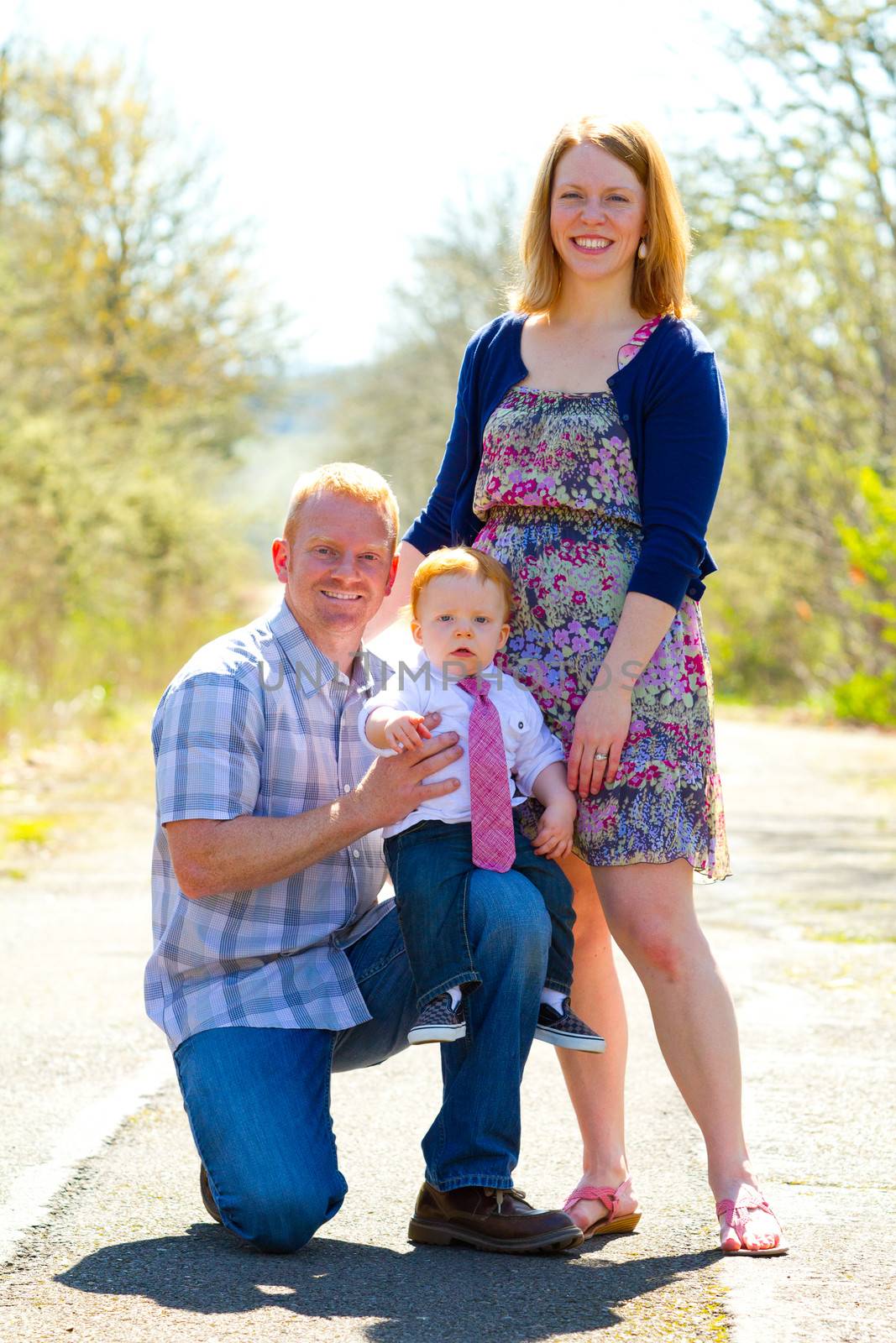 A family of three people together outdoors wearing nice clothes in this simple portrait.