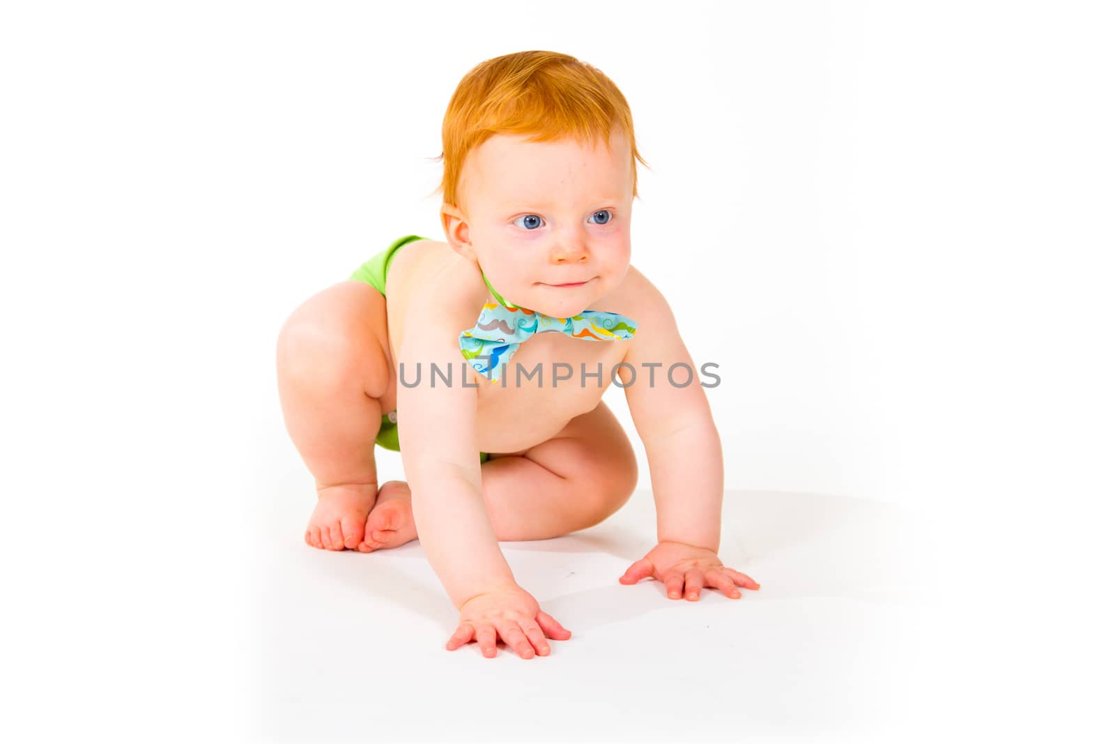 A one year old baby boy in the studio with a white background. The kid is wearing a bowtie and a diaper.