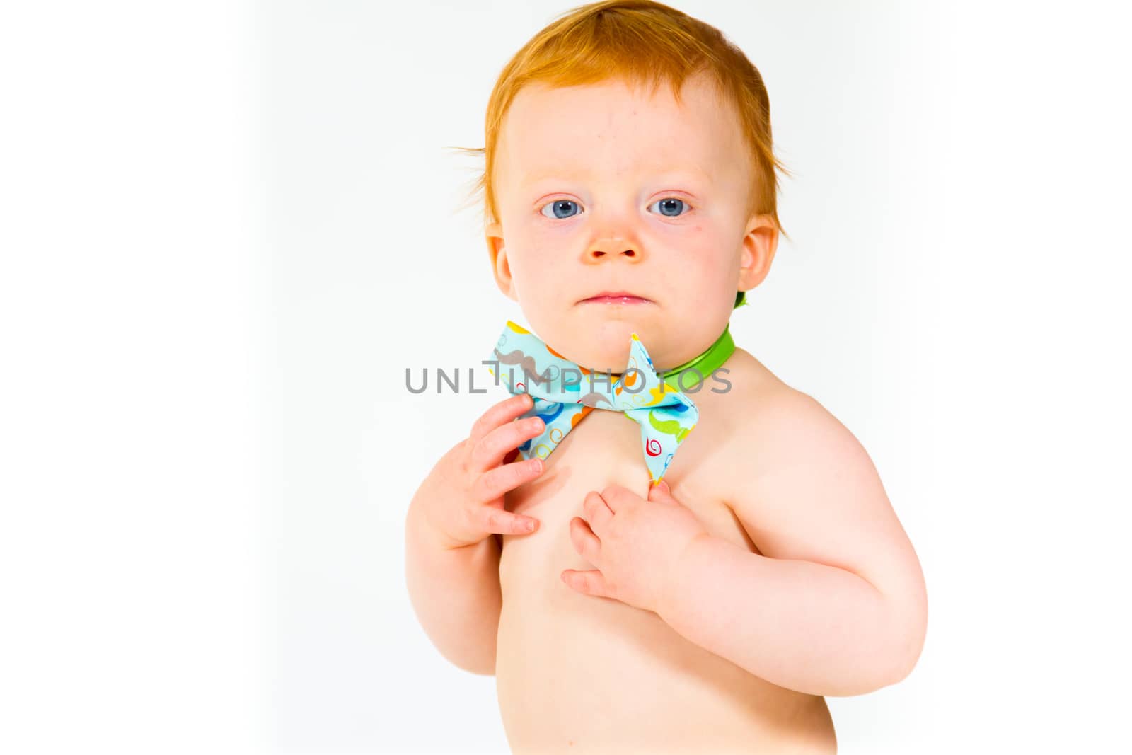 A one year old baby boy in the studio with a white background. The kid is wearing a bowtie and a diaper.
