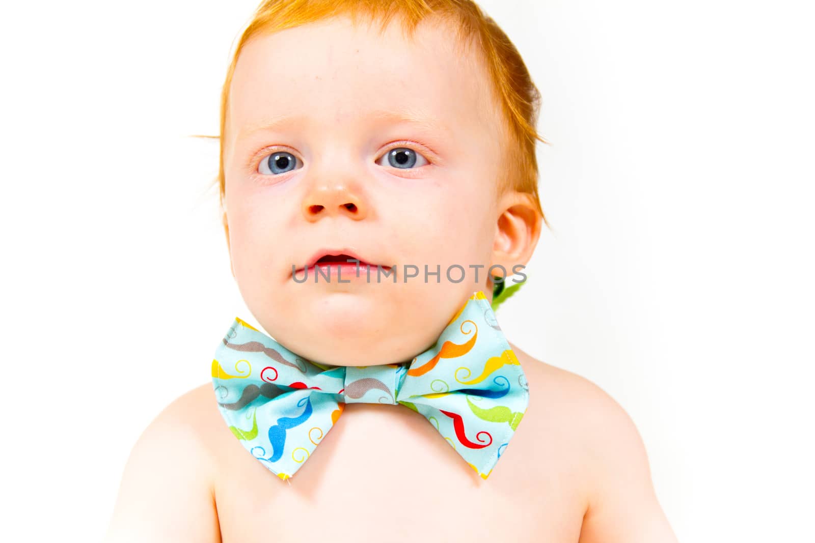 A one year old baby boy in the studio with a white background. The kid is wearing a bowtie and a diaper.