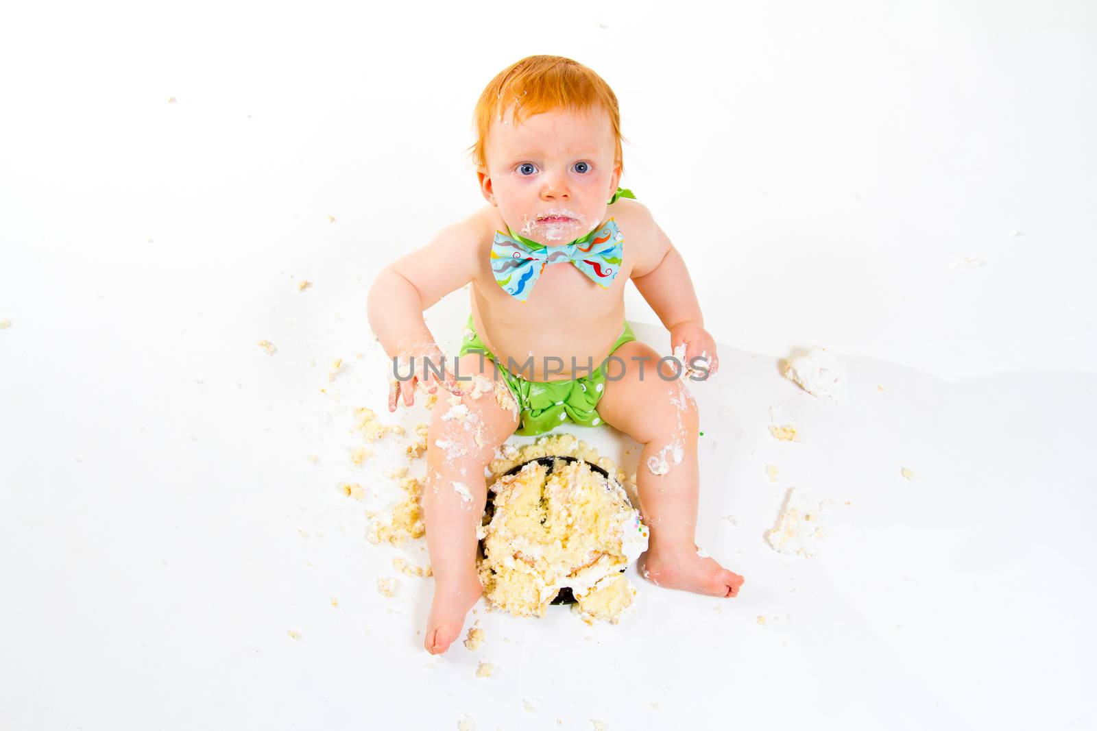 A baby boy gets to eat cake for the first time on his first birthday in this cake smash in studio against a white background.