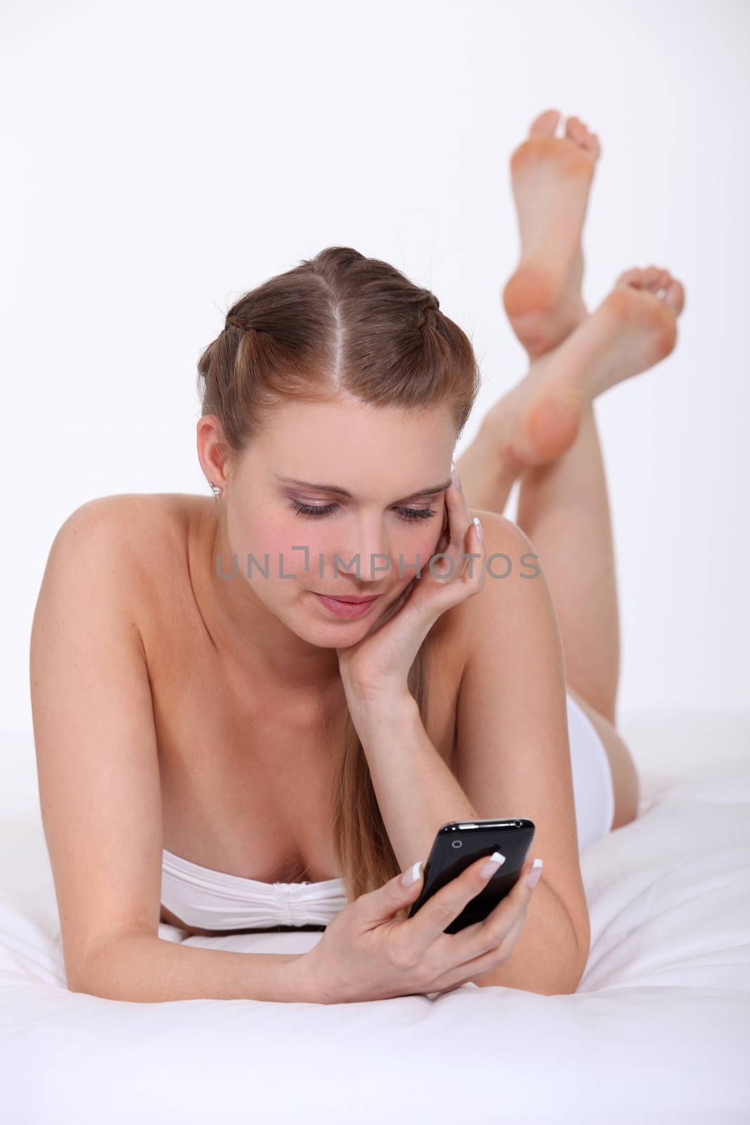 Woman in bed with a cellphone by phovoir