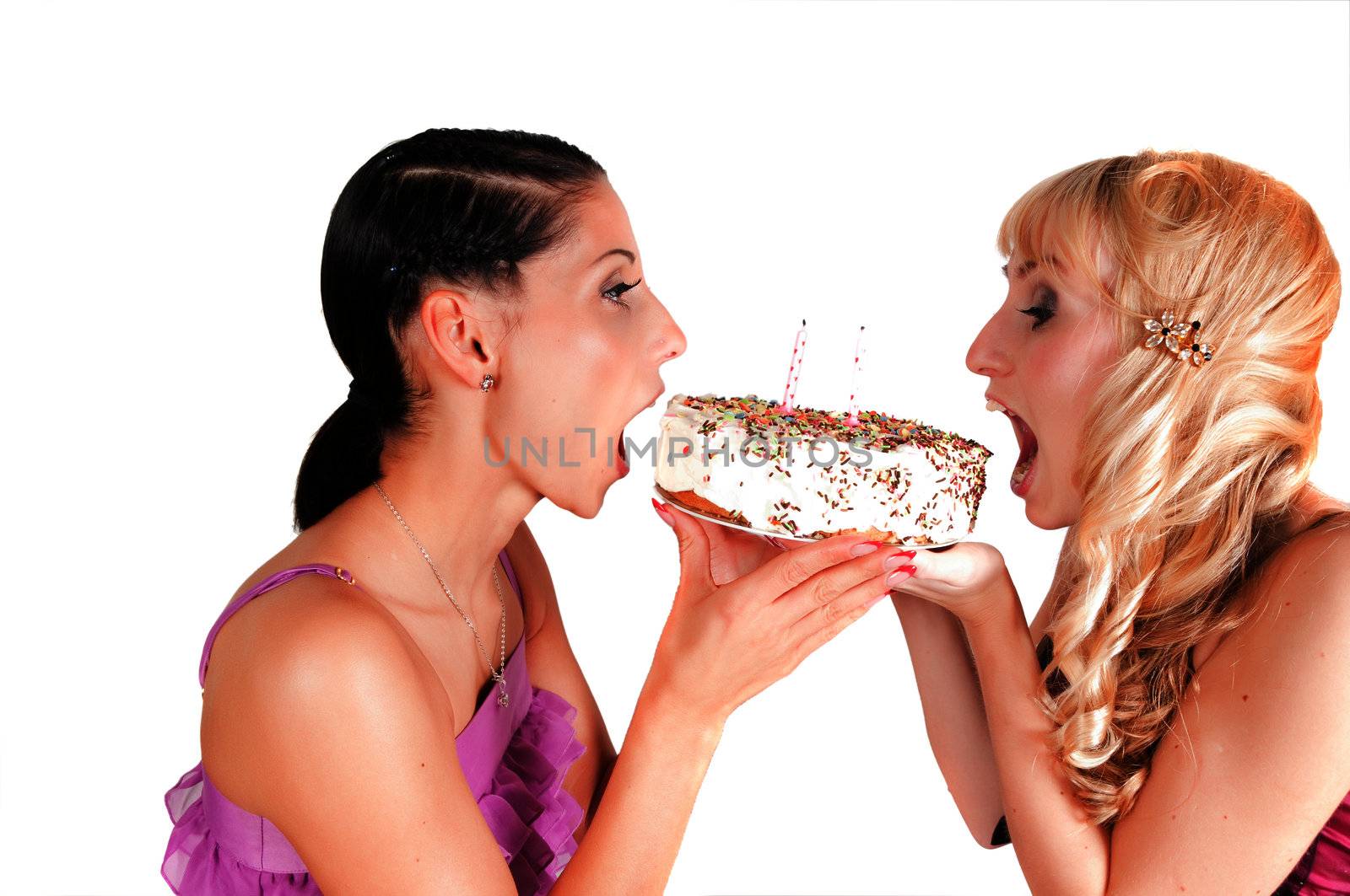 Two girls eating the cake on the girl's party, isolated on white