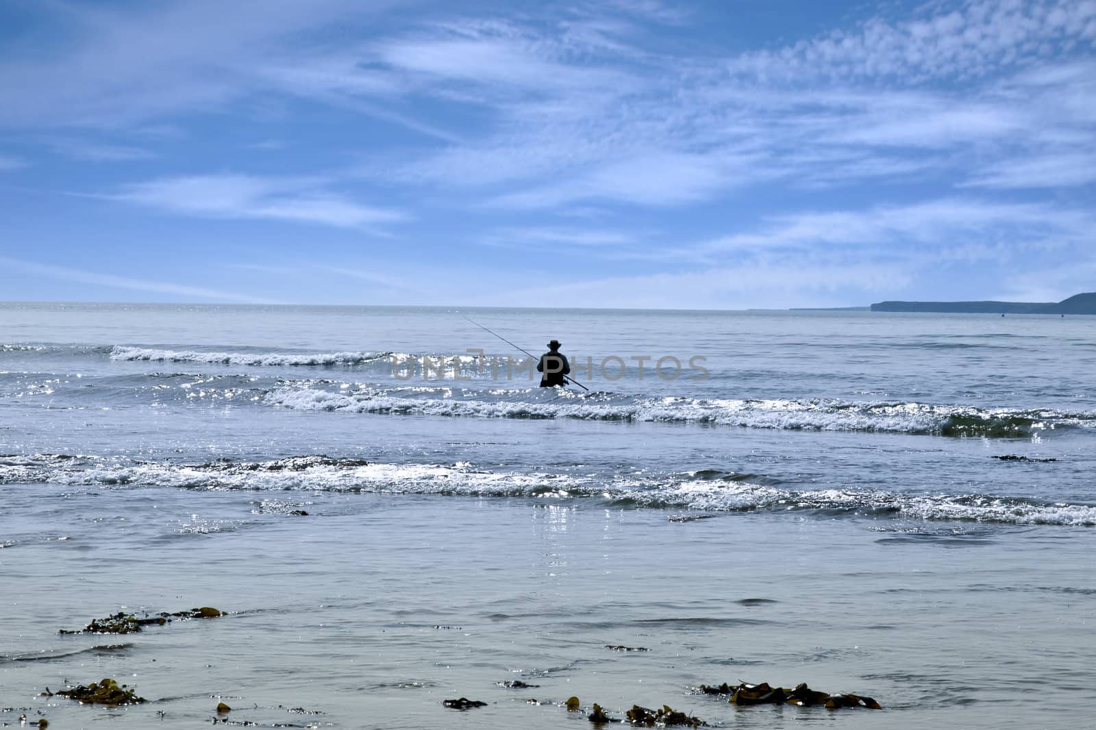 lone man fishing in the river Shannon estuary waves in Ballybunion county Kerry Ireland