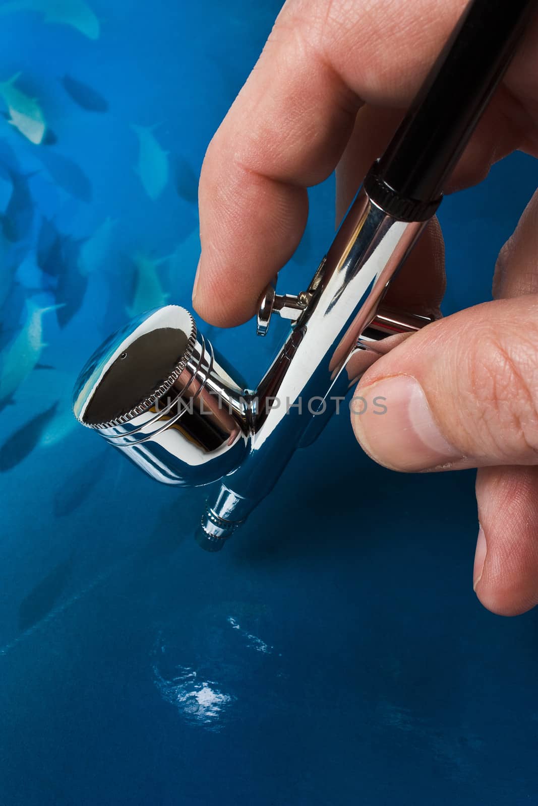 Airbrush in hand on blue background