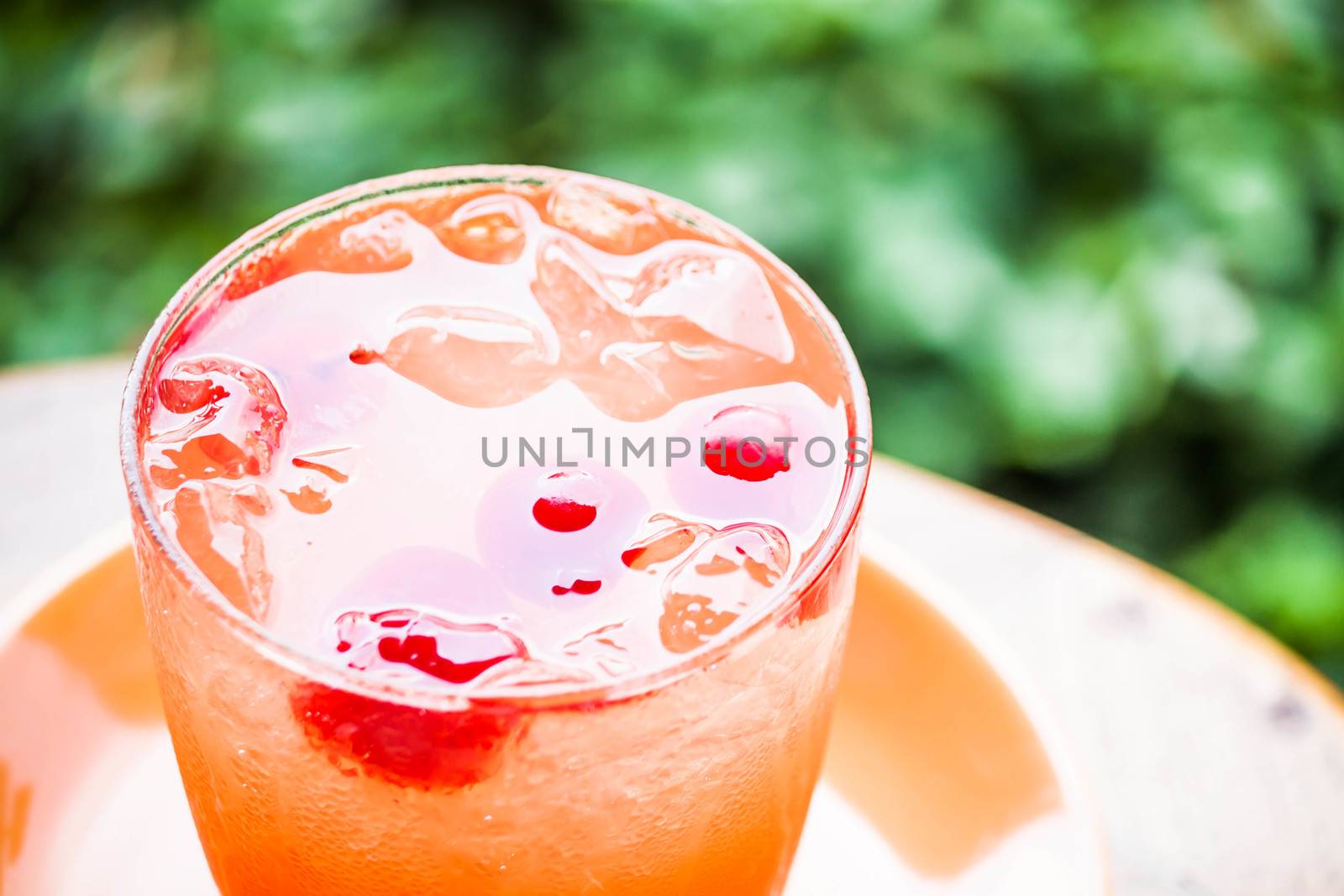 Glass of iced mix fruits juice soda on green background