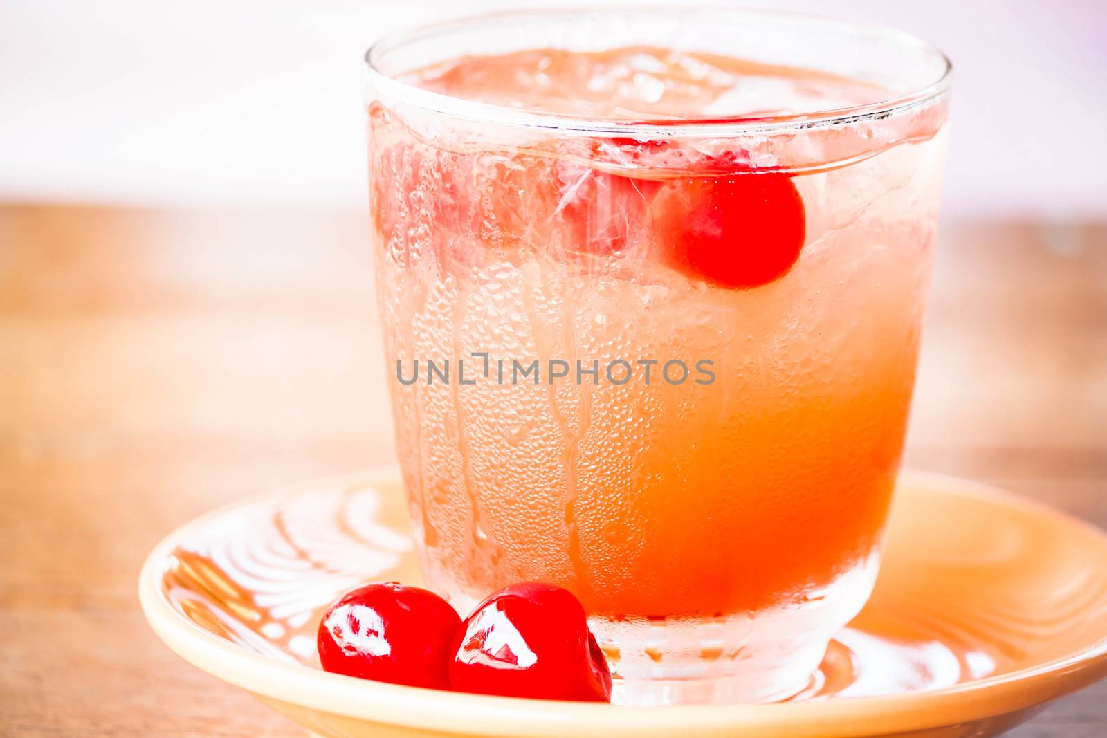 Glass of cold mix fruits juice soda on wood table by punsayaporn