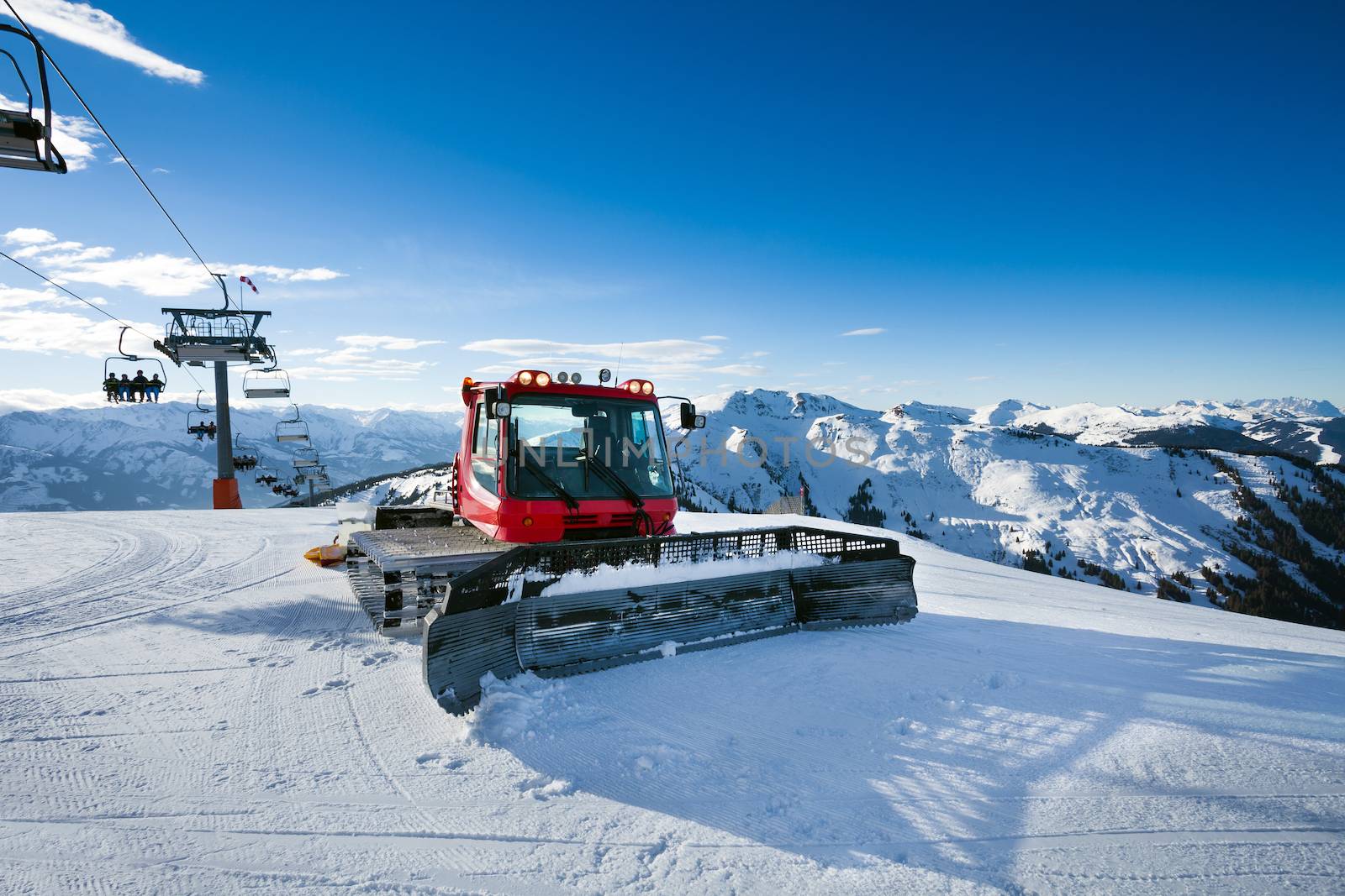 Snow-grooming machine on snow hill ready for skiing slope preparations in Austrian Alps.