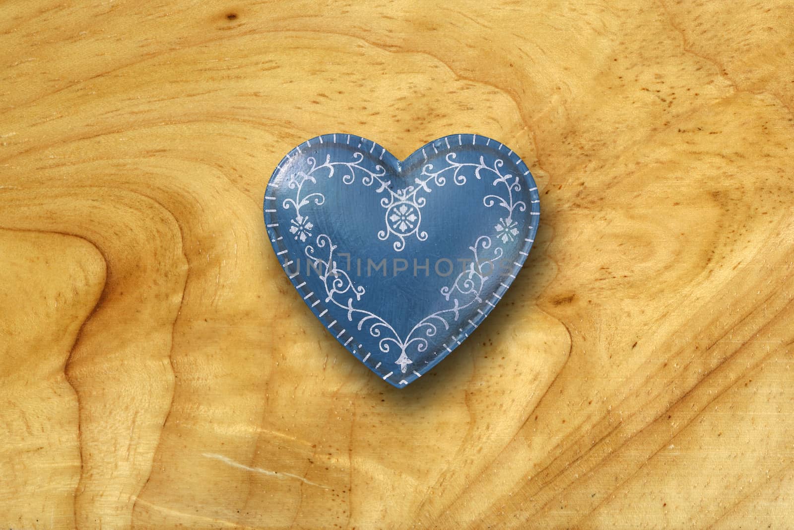 Photo of a blue ornate heart on top of an old wood background.
