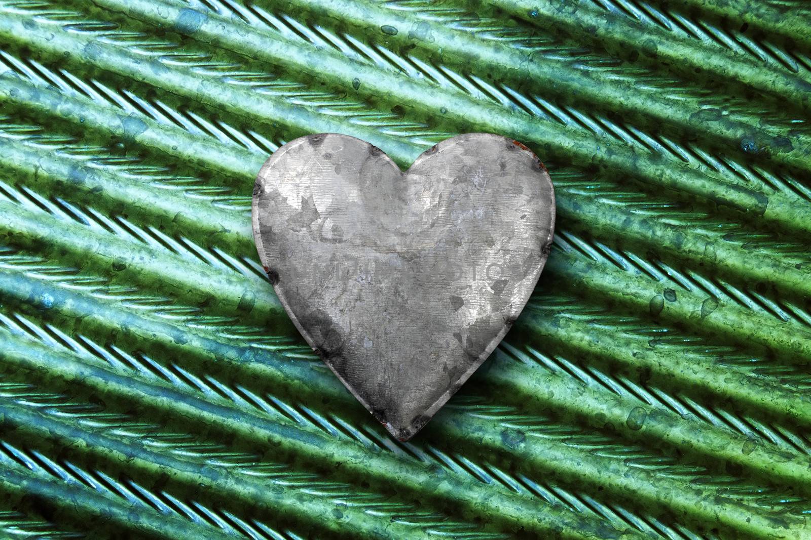 Photo of a galvanized metal heart on top of green metal background.
