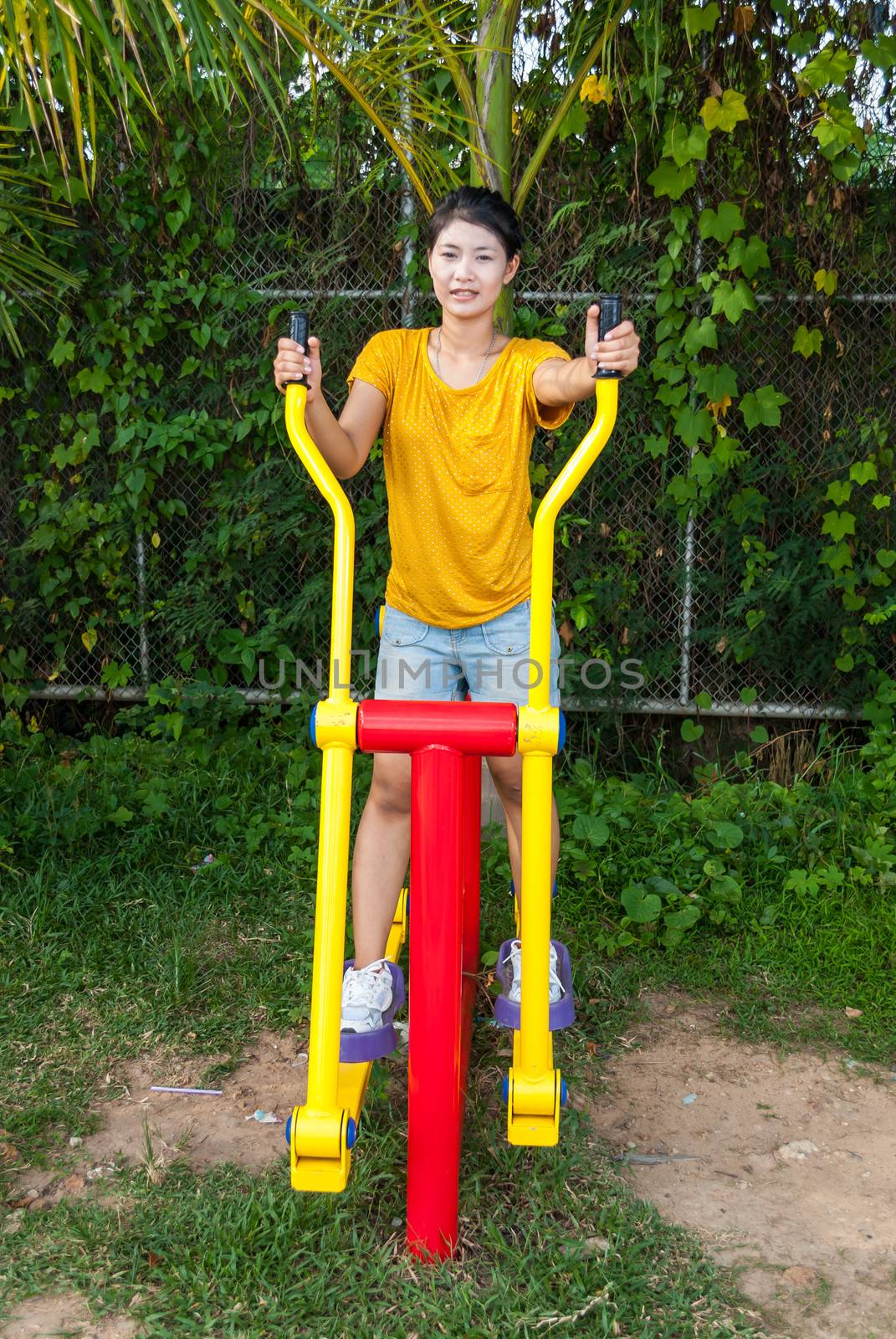 Asian Thai Girl with Exercise Machine in Public Park.