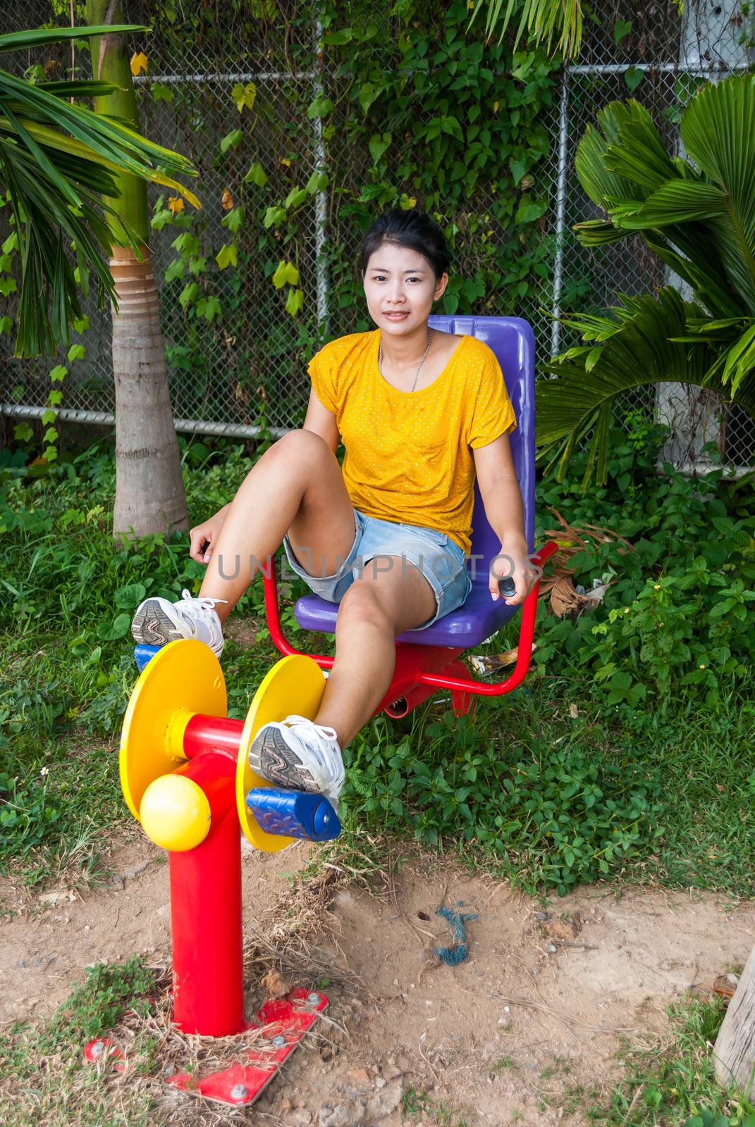 Asian Thai Girl with Exercise Machine in Public Park.