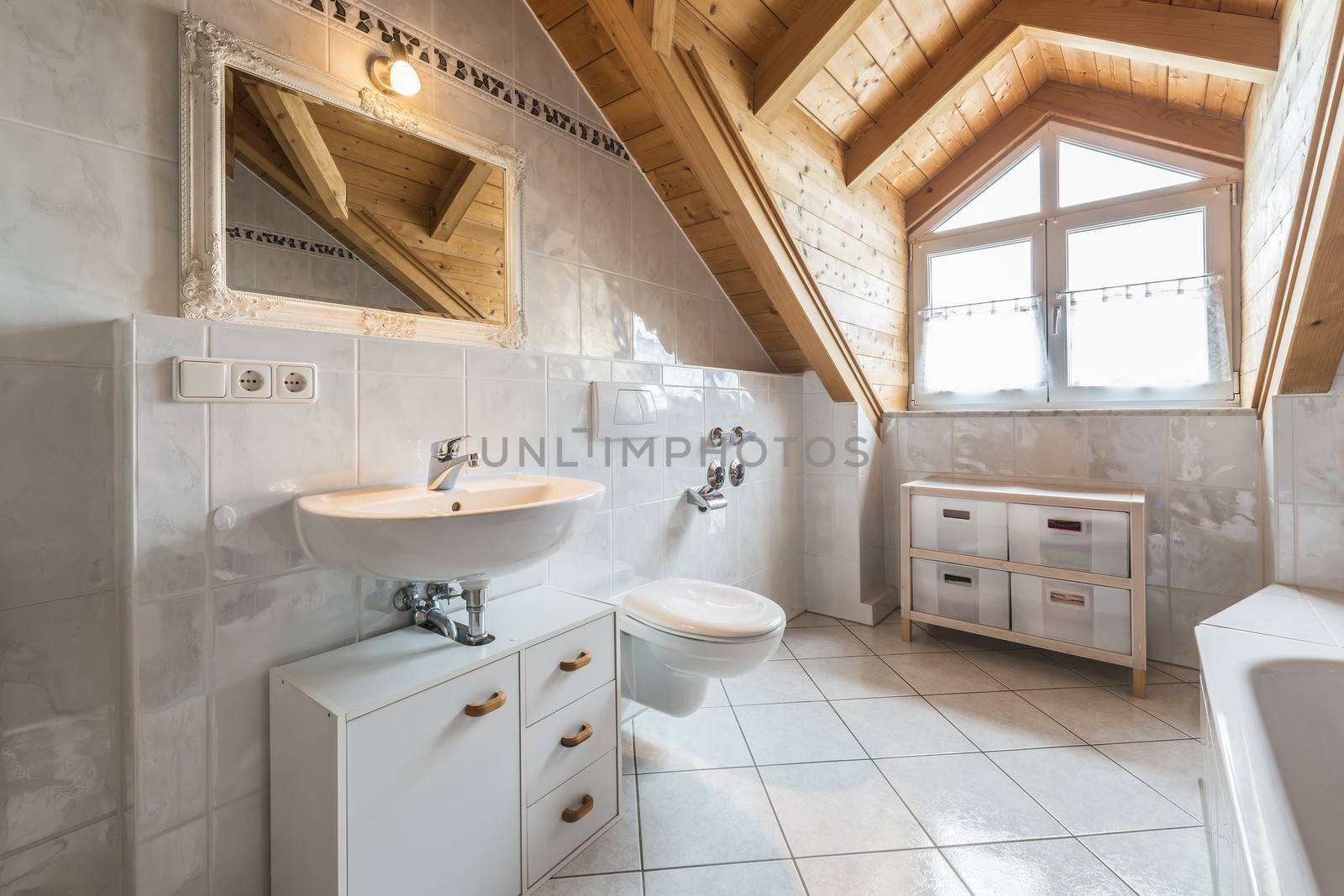 bathroom of a flat in attic with basin, mirror, light, window, toilet, bathtub, cabinets and wooden ceiling