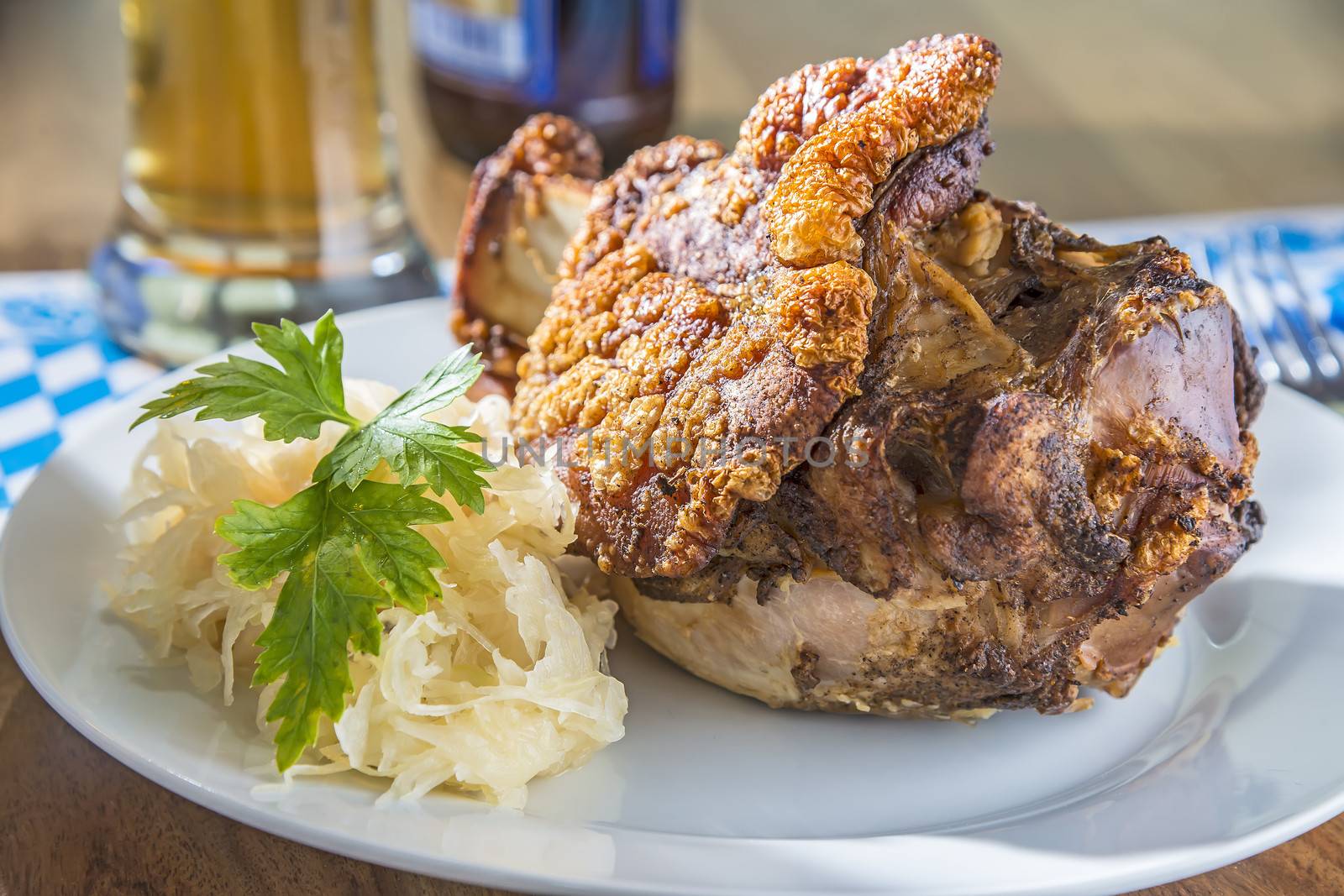 Oktoberfest pork hock with cabbage on a table with beer and Bavarian white blue napkin