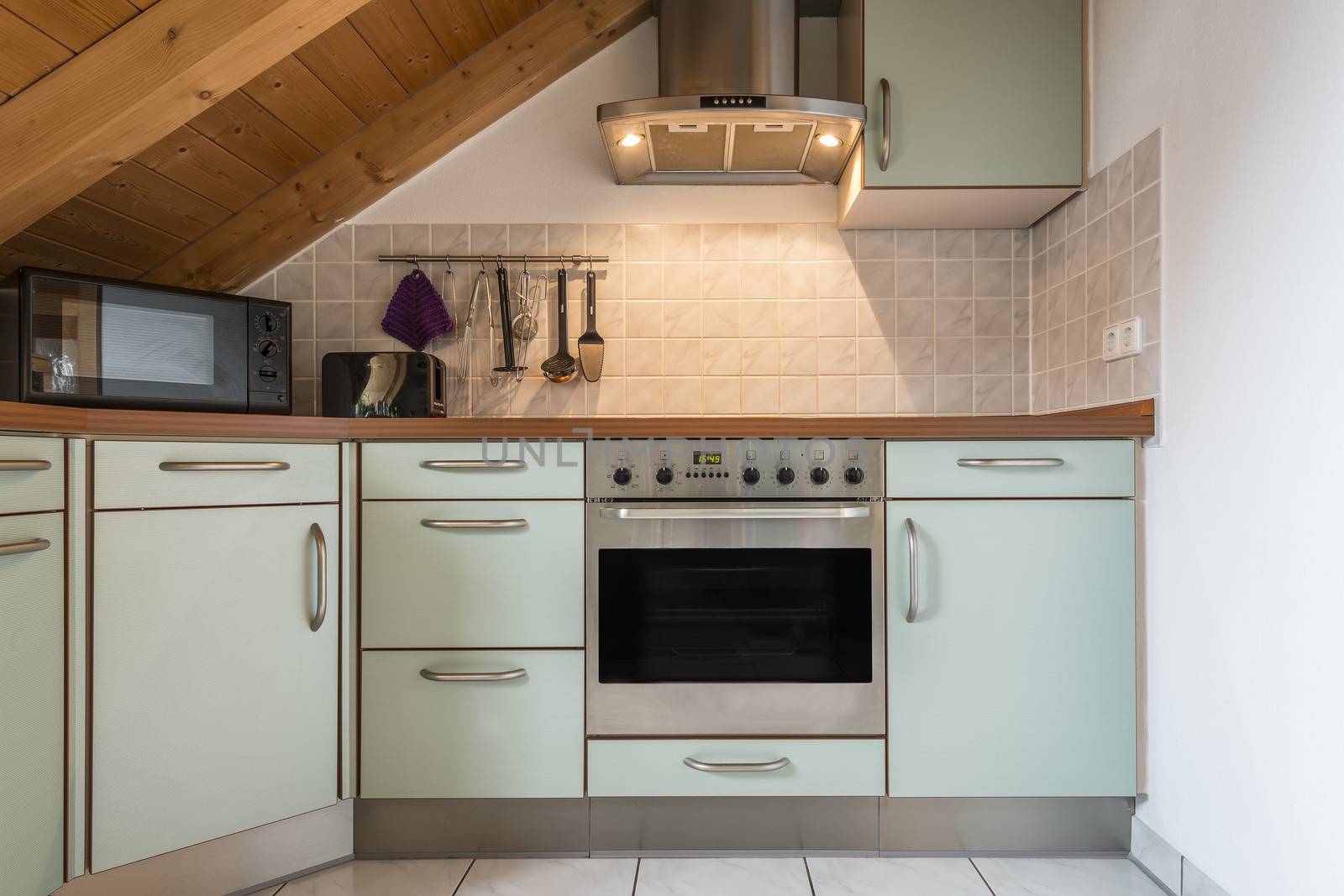 kitchen of a flat with oven, microwave, stove, hood, cabinets and wooden ceiling