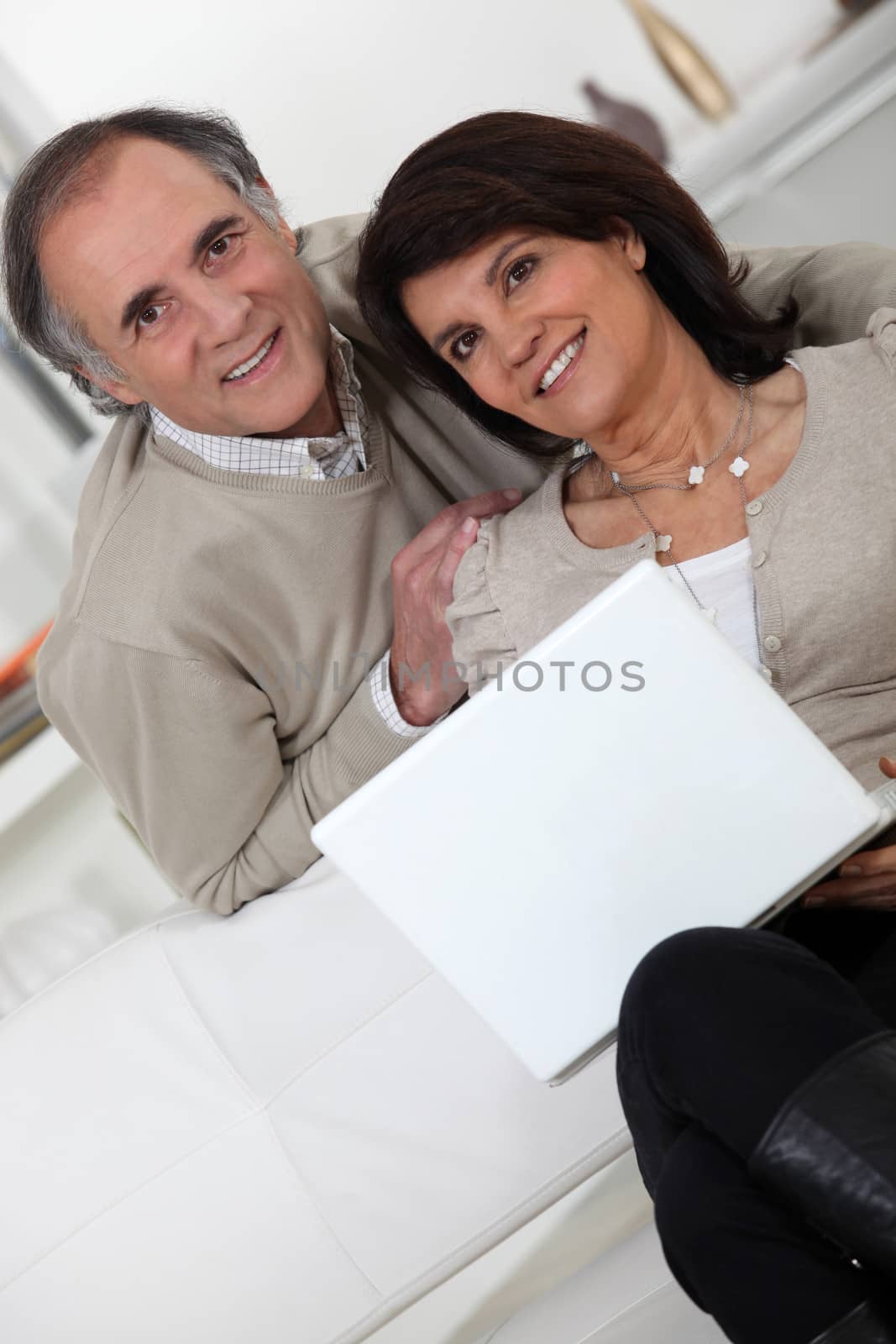 Married couple sat on the sofa with laptop by phovoir
