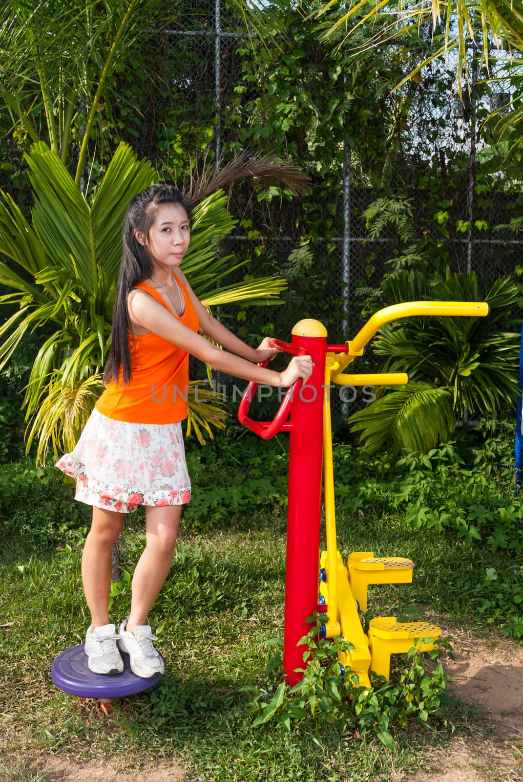 Asian Thai Girl with Exercise Machine in Public Park.