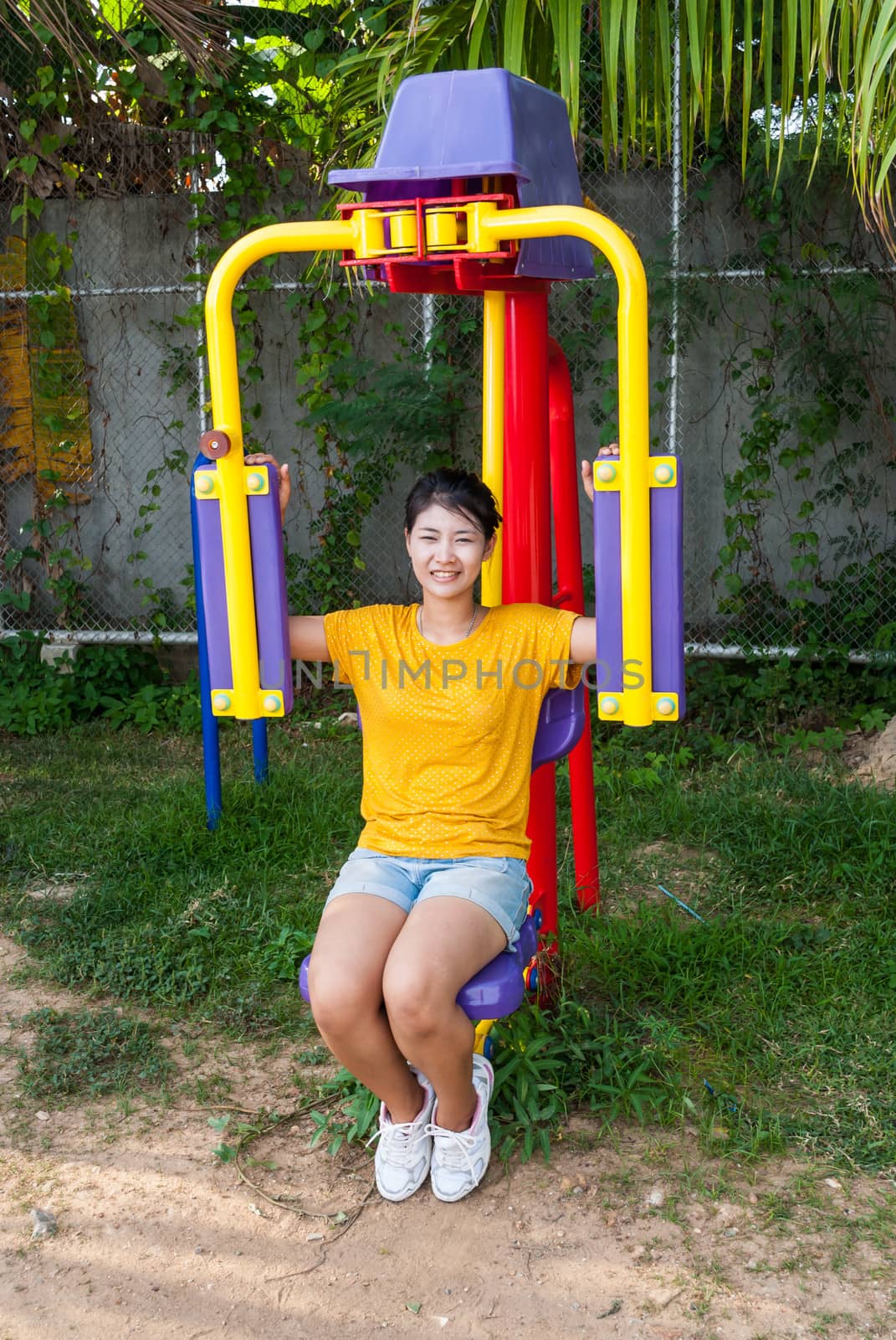 Asian Thai Girl with Exercise Machine in Public Park.