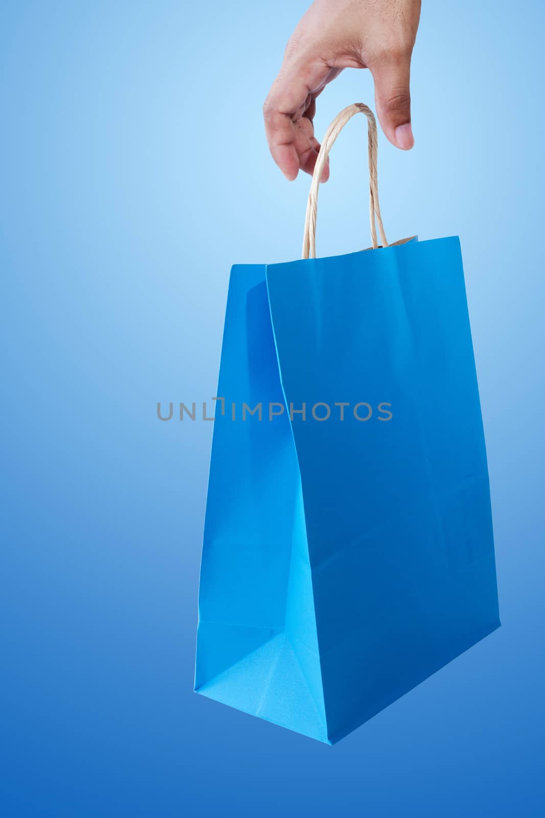 Hand and shopping bag on blue background