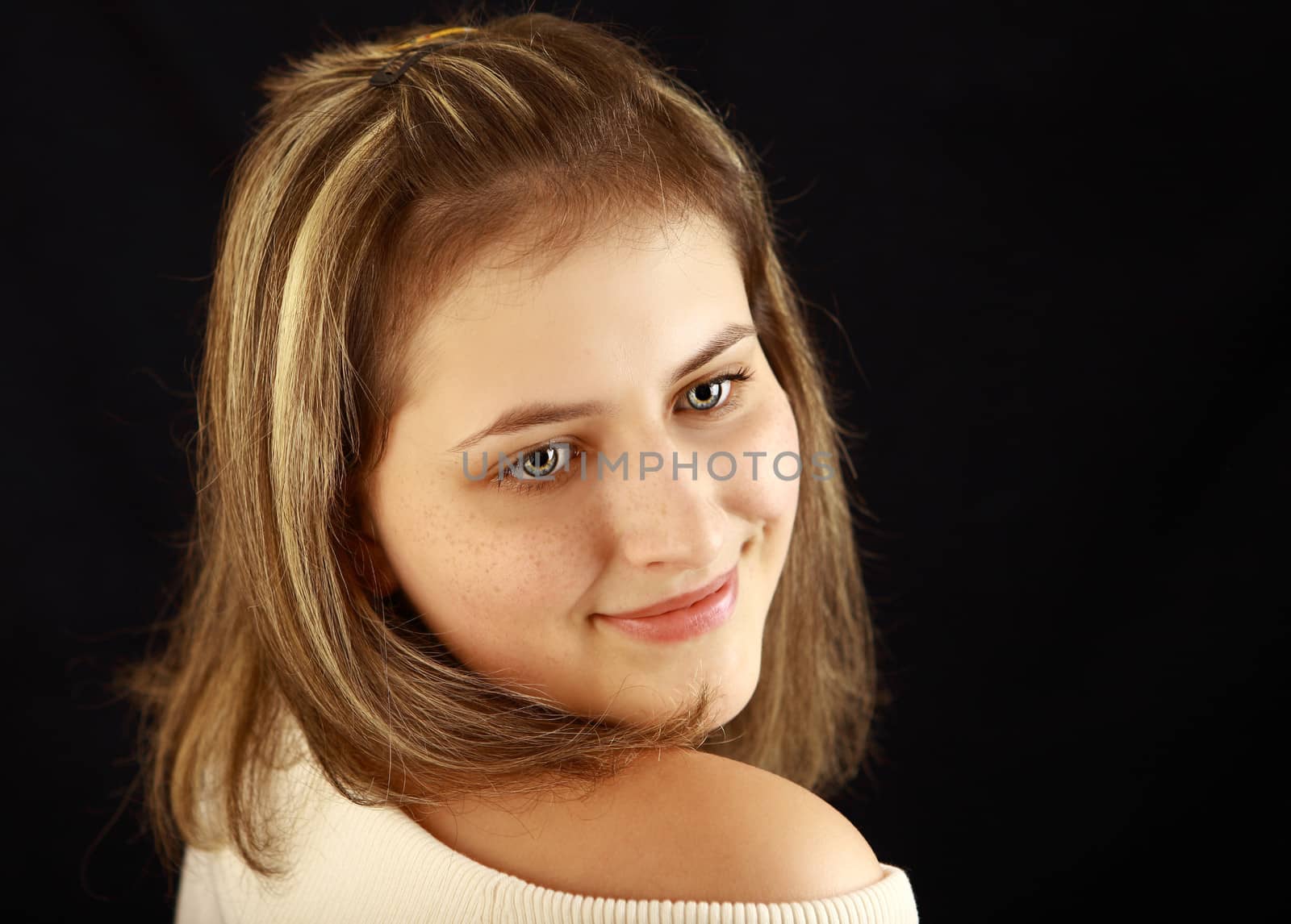 Girl with freckles, 17 years old, gray eyes, hairstyle with highlights, a white shirt, open shoulder, looking to the right, the horizontal image on a black background.