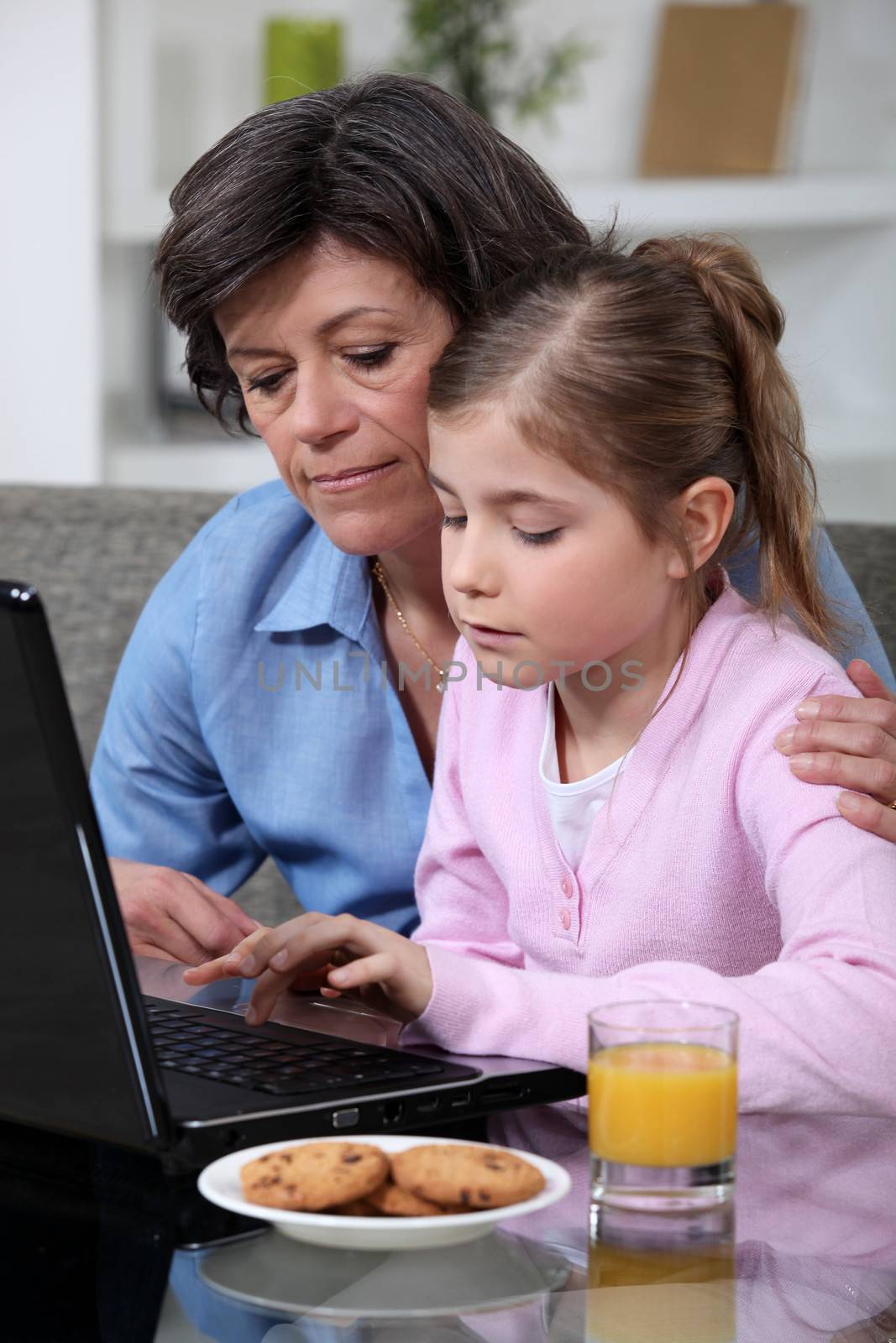 Child and her grandmother using a laptop by phovoir