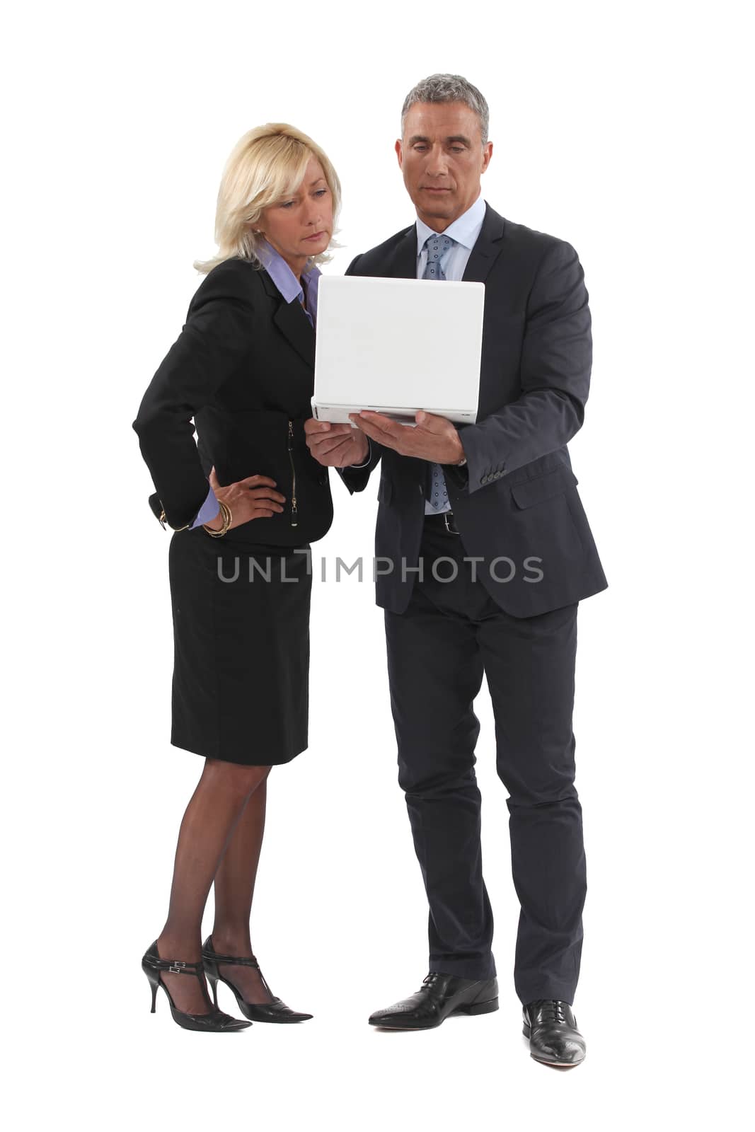 Senior business couple stood with laptop by phovoir