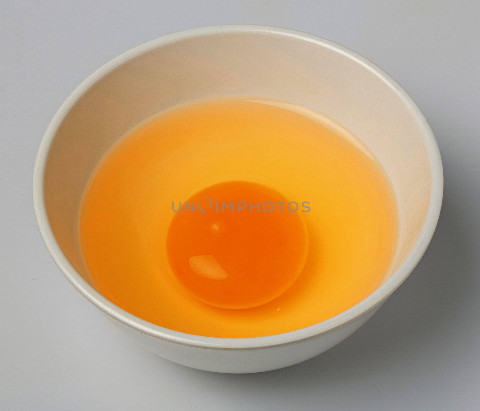 Chicken egg yolk in white small bowl