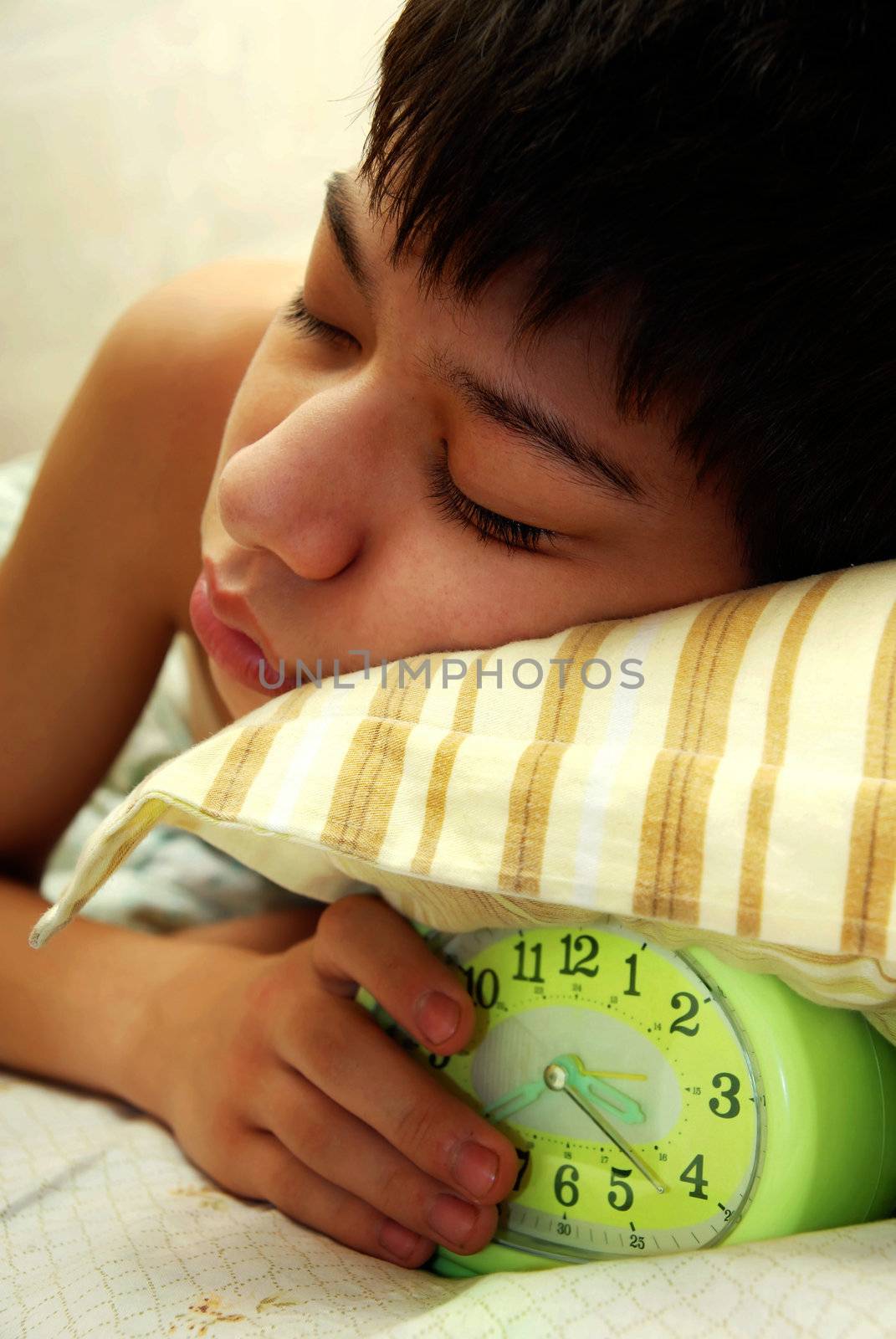 Deep sleep of the boy with green alarm-clock