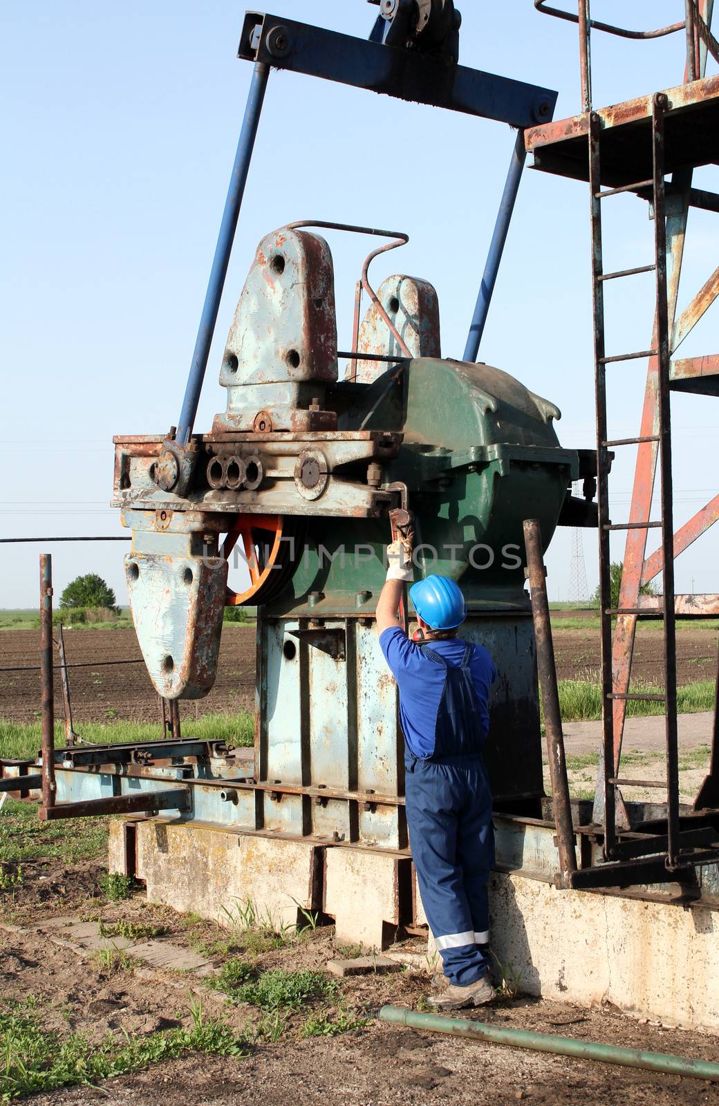 oil worker with pipe wrench working by goce
