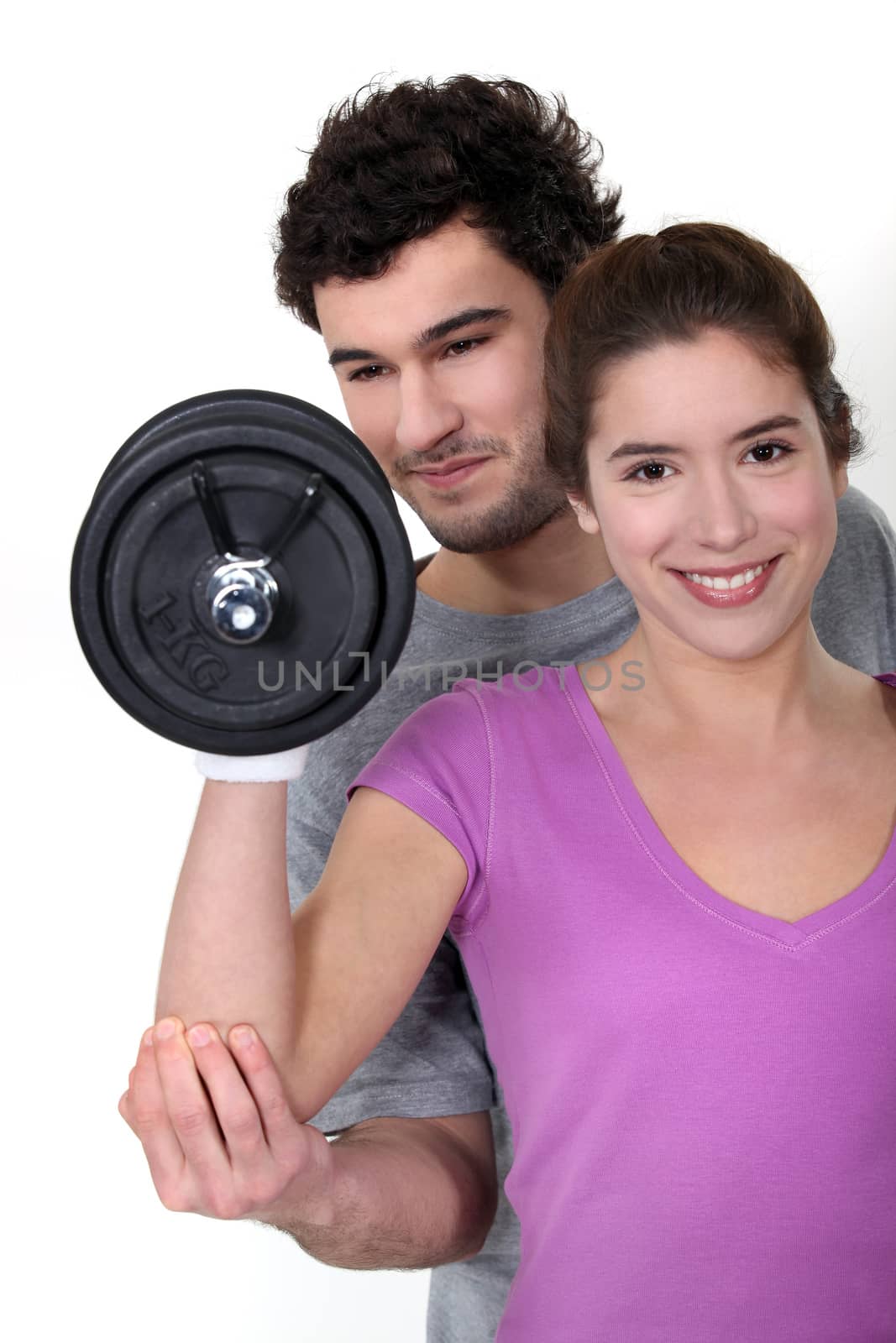 coach and young woman all smiles lifting weight