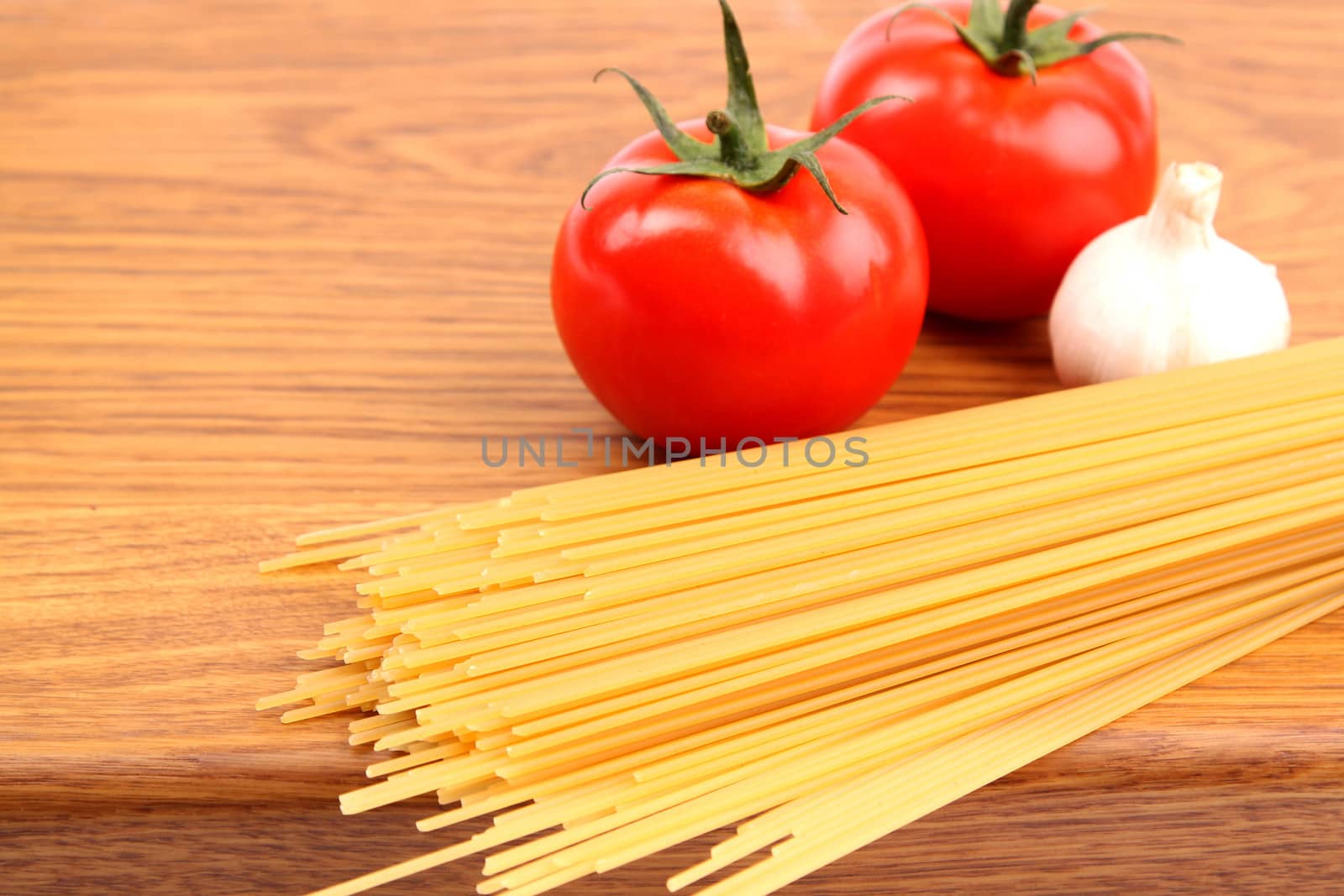 uncooked spaghetti, garlic and tomatos on a preparation board by indigolotos