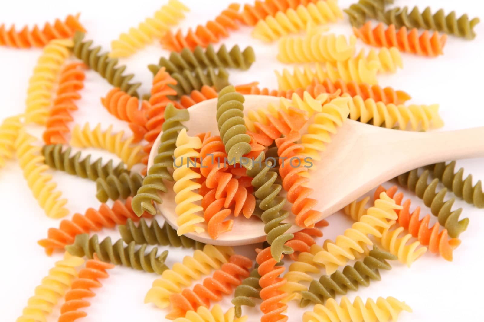 A pasta eliche tricolori and a wood spoon.