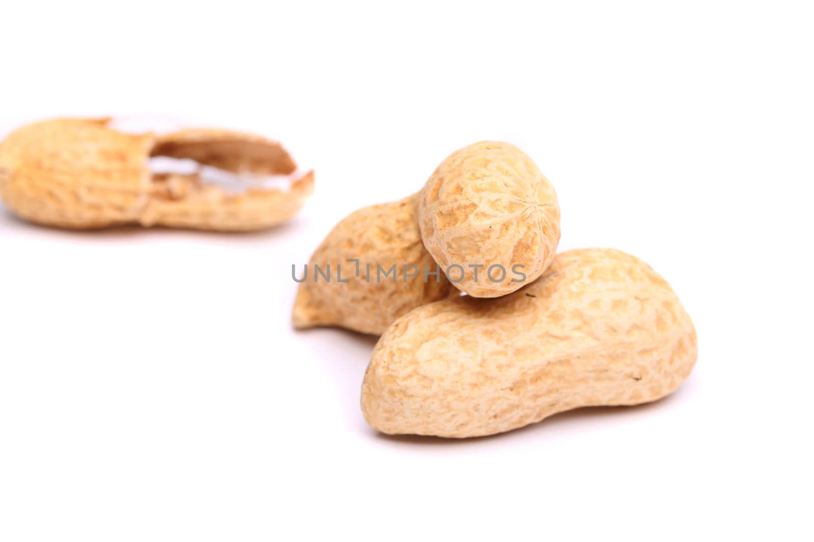 Three peanuts in closeup and peel on the white background
