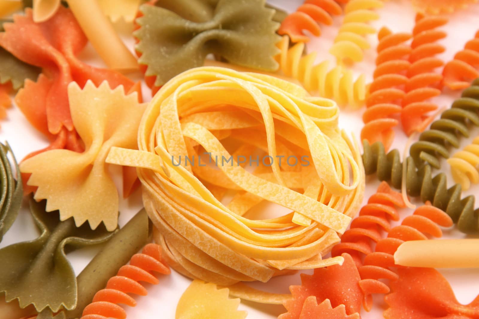 Yellow tagliatelle paglia e fieno on the backgroun of different pastas. by indigolotos