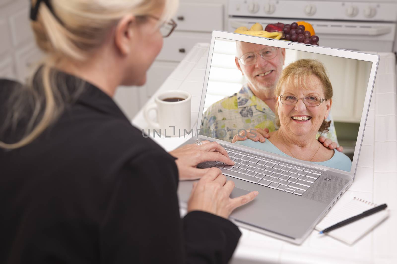 Woman In Kitchen Using Laptop - Online Chat with Senior Couple or Parents On Screen.