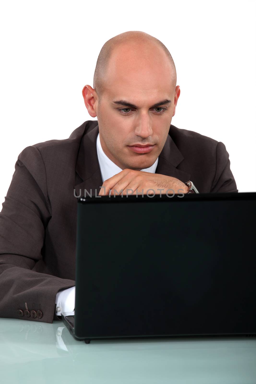 Bald office worker sat at computer by phovoir