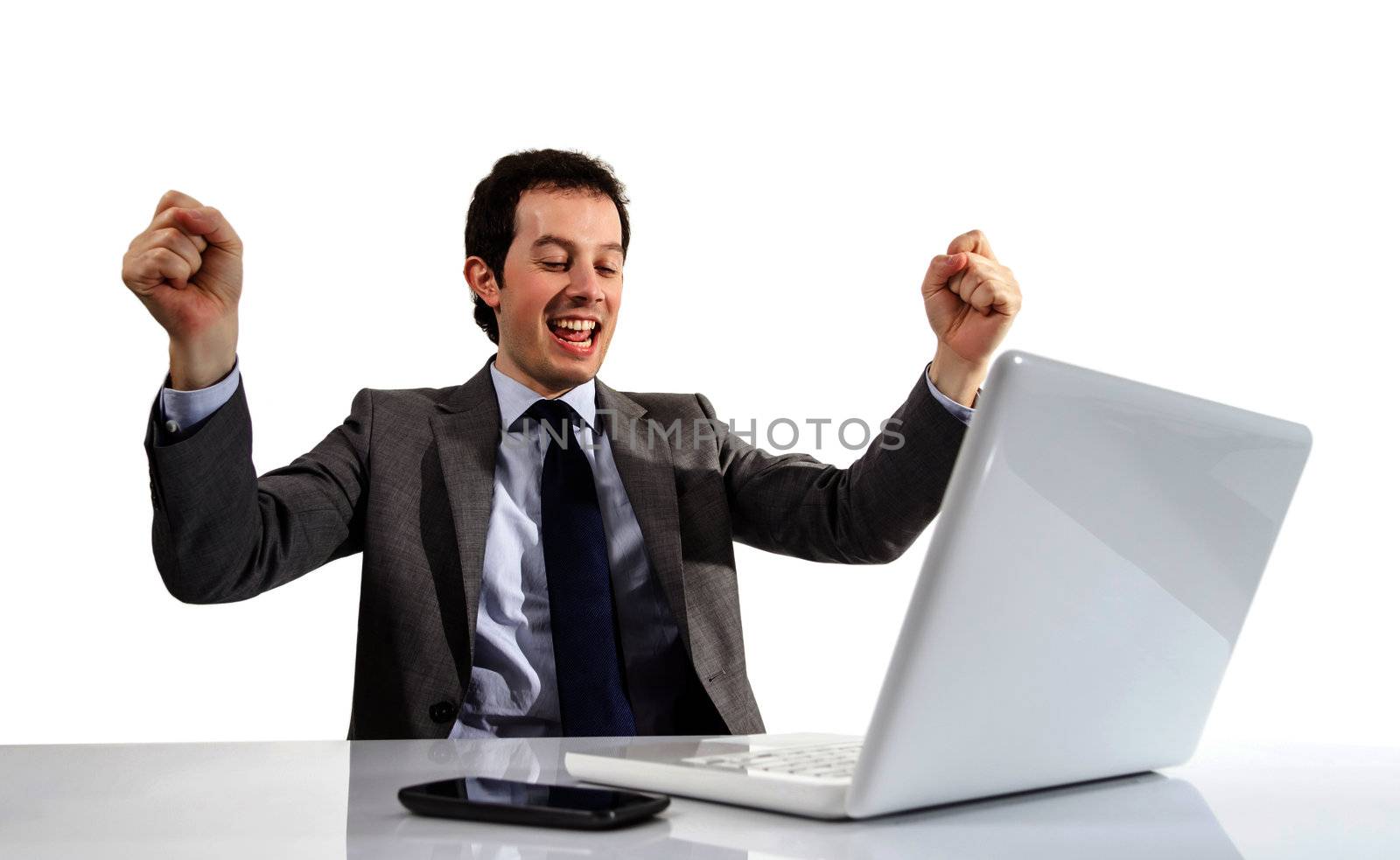 Happy young executive man looking a laptop computer with arms raised in success, over a white backgroud
