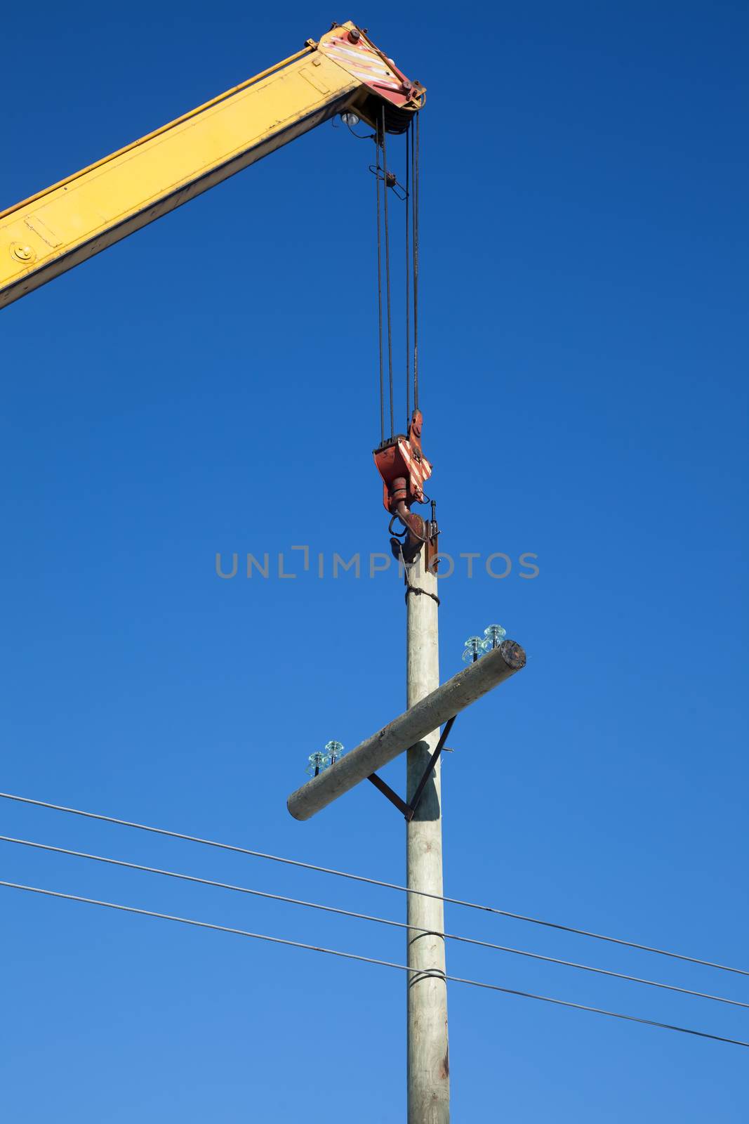 Installation of wooden electric poles crane. When the sunlight against the blue sky