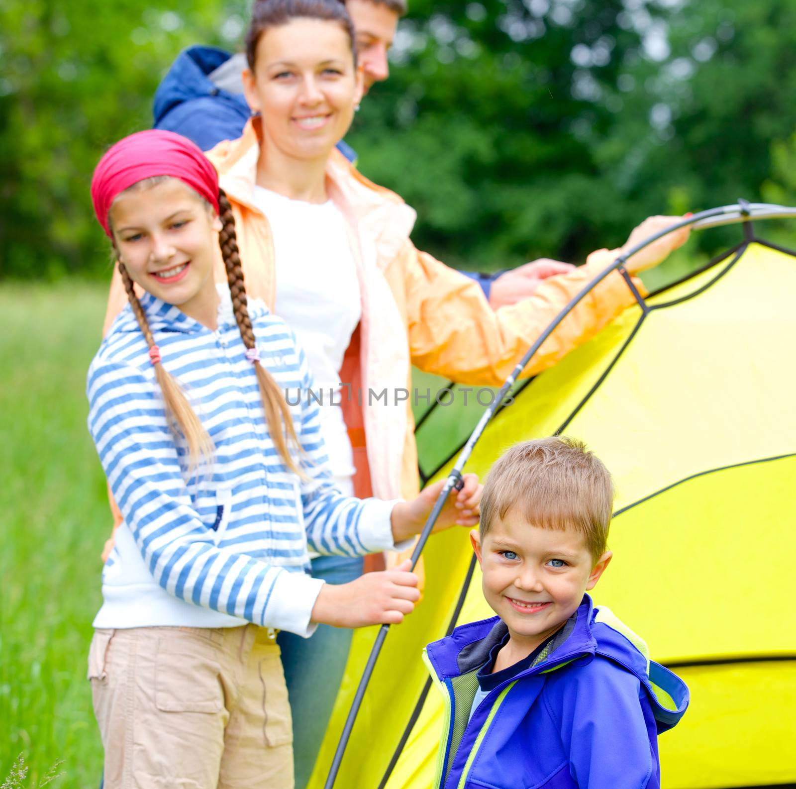 Young boy with his family near tent in camping on the nature