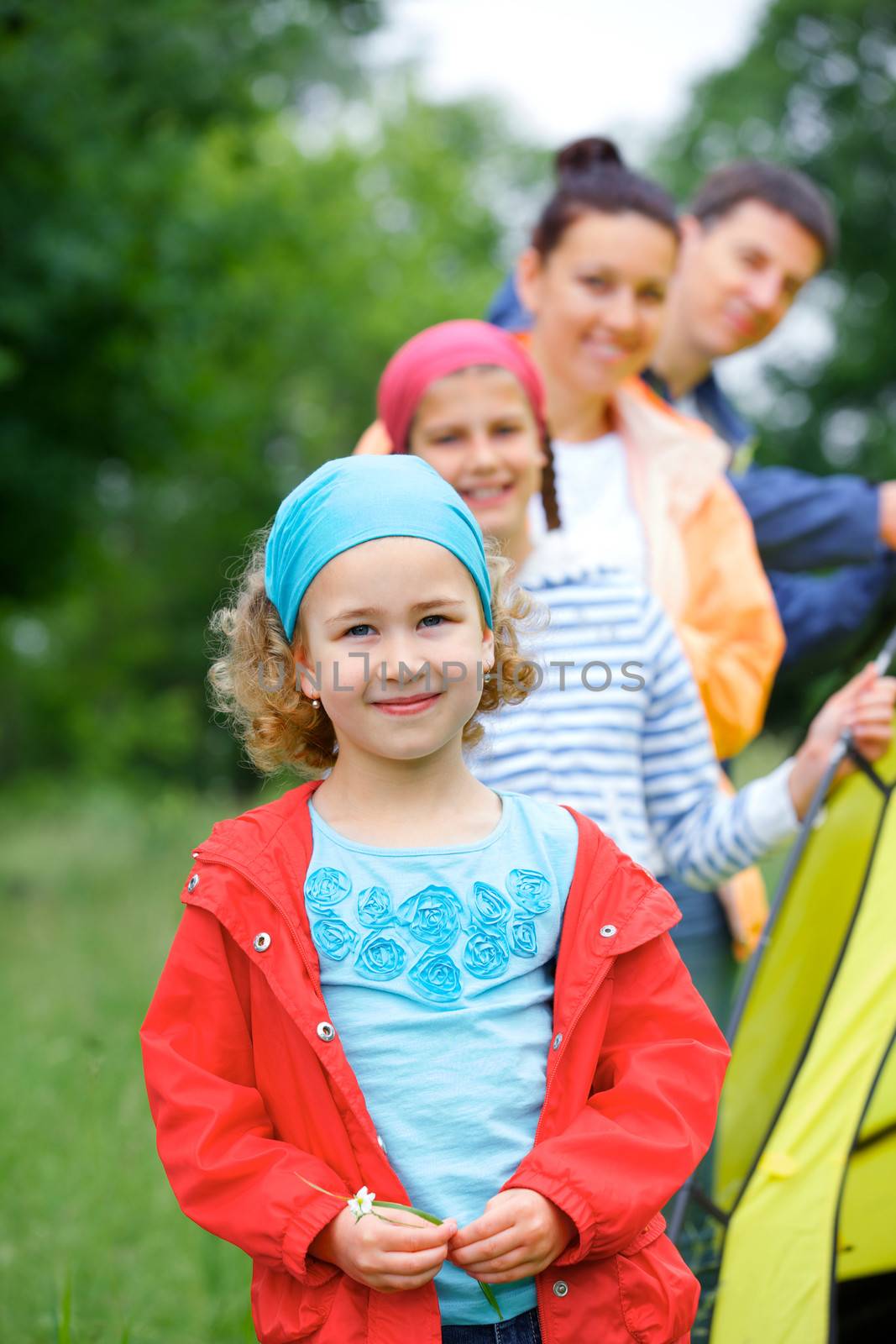 Young girl with her family near tent in camping on the nature