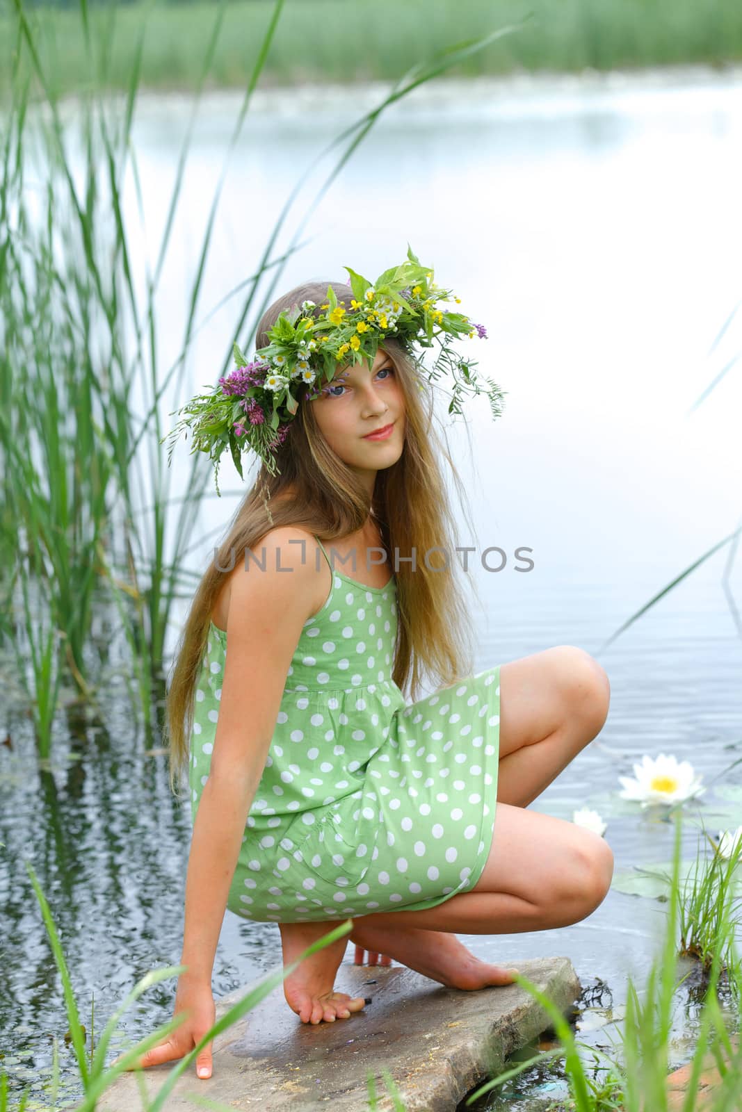 Spring beautiful girl with wreath of flowers near forest lake