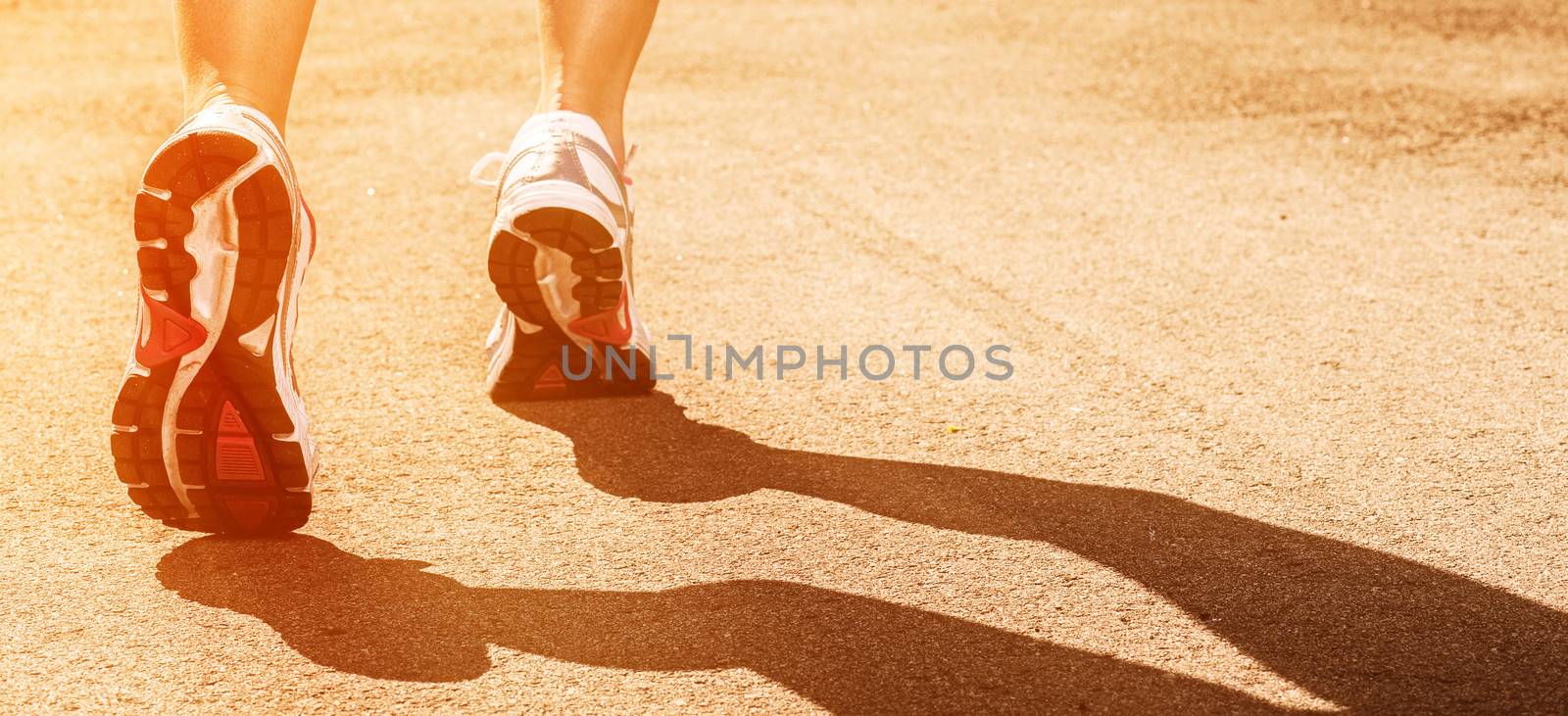 Woman legs in sneakers on asphalt background