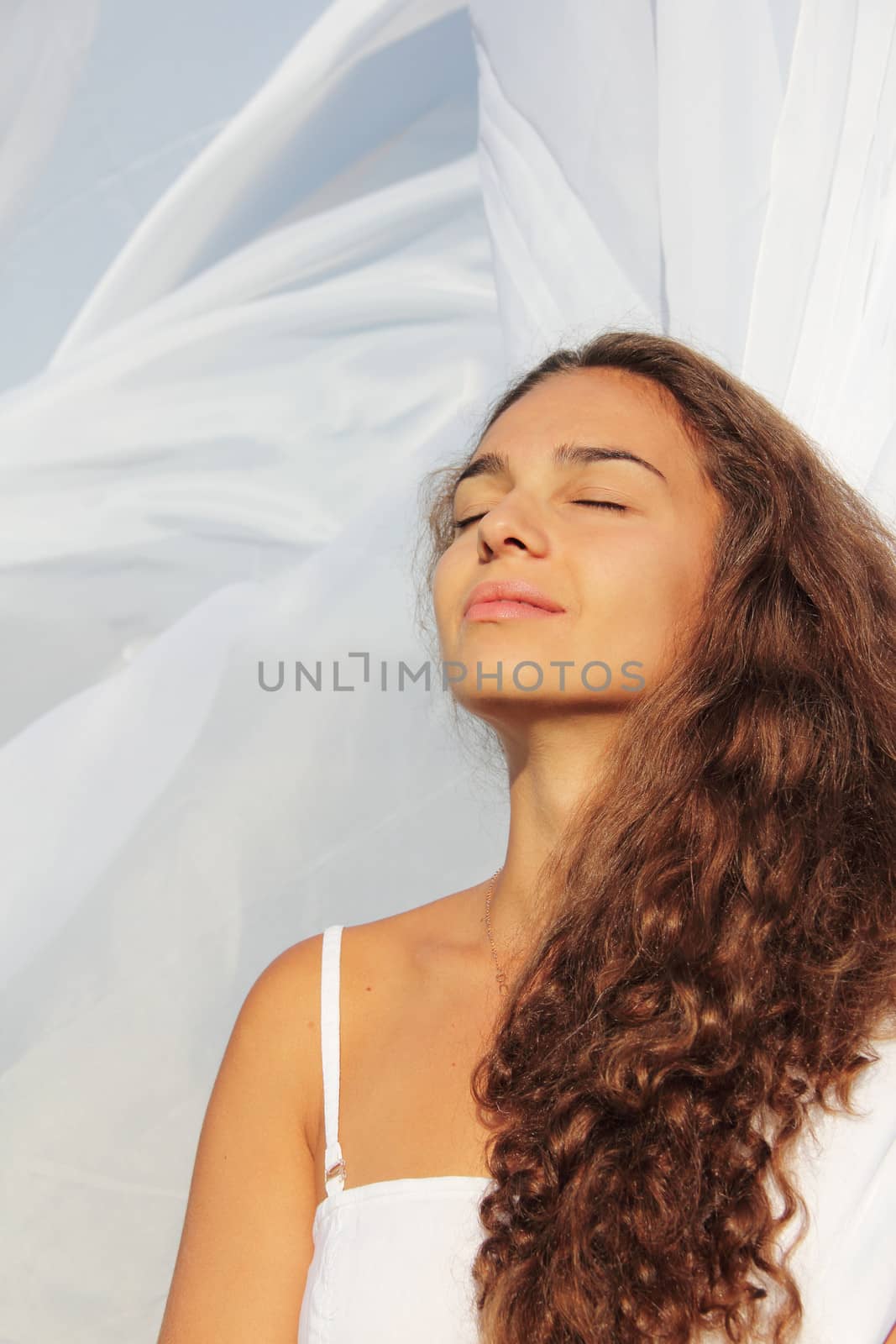 Beautiful young woman with closed eyes on white fabric background