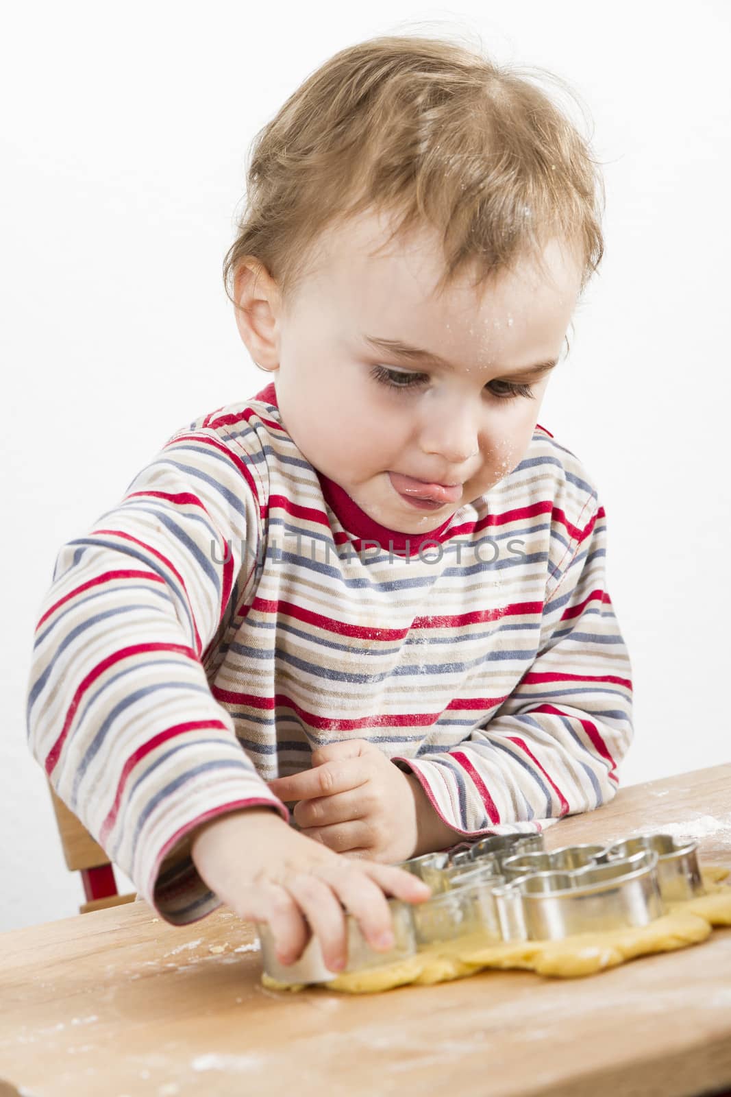 child at wooden desk making cookies. vertical image