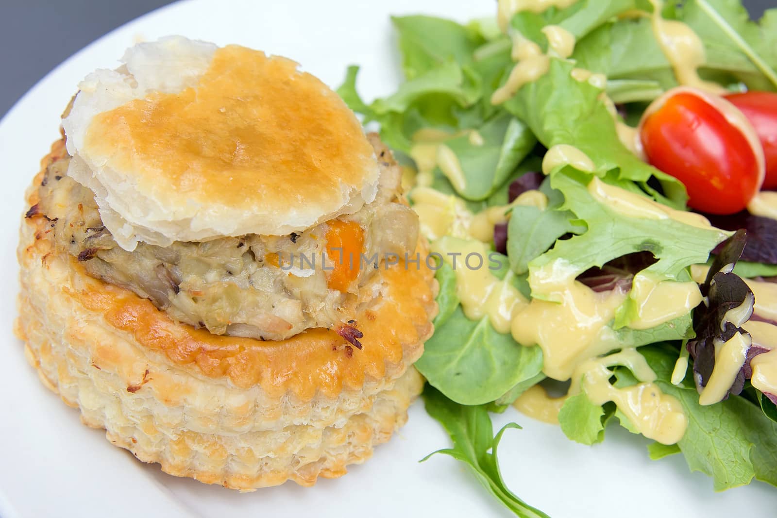 Chicken Pot Pie with Leafy Green Vegetables Tomatoes and Salad Dressing Closeup