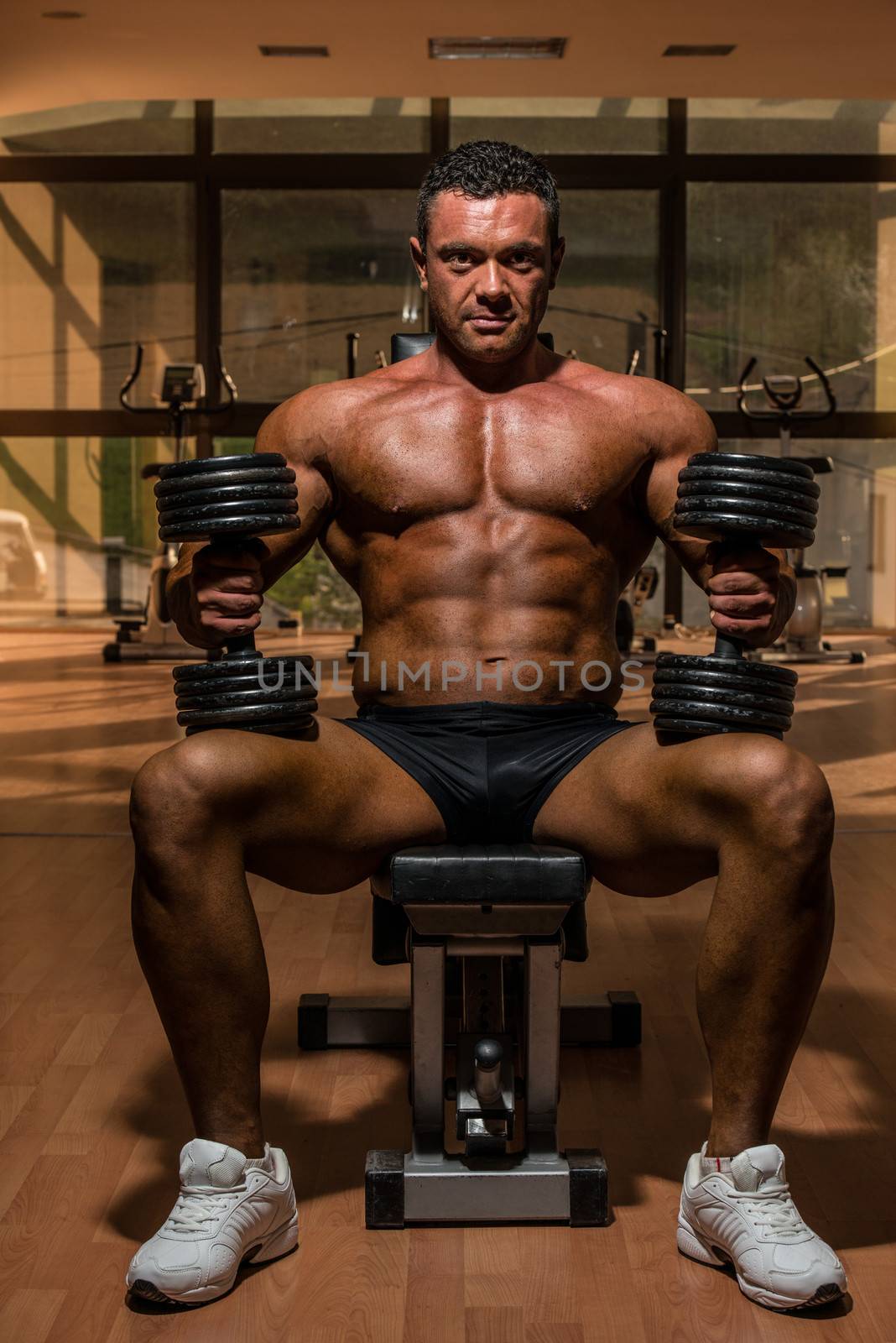 male bodybuilder resting after doing heavy weight exercise by JalePhoto