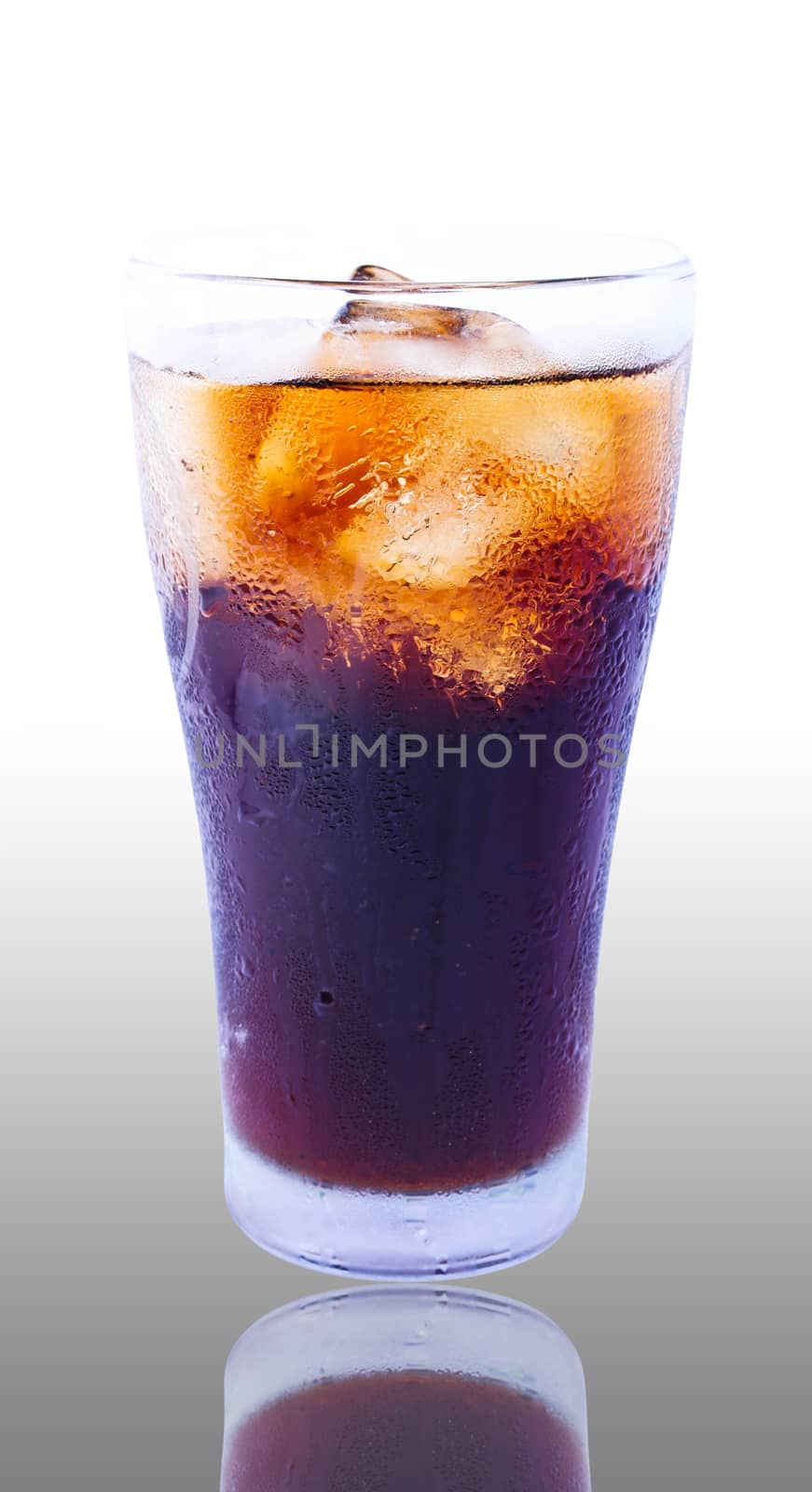 Glass filled with ice cubes and Cola soda over a white