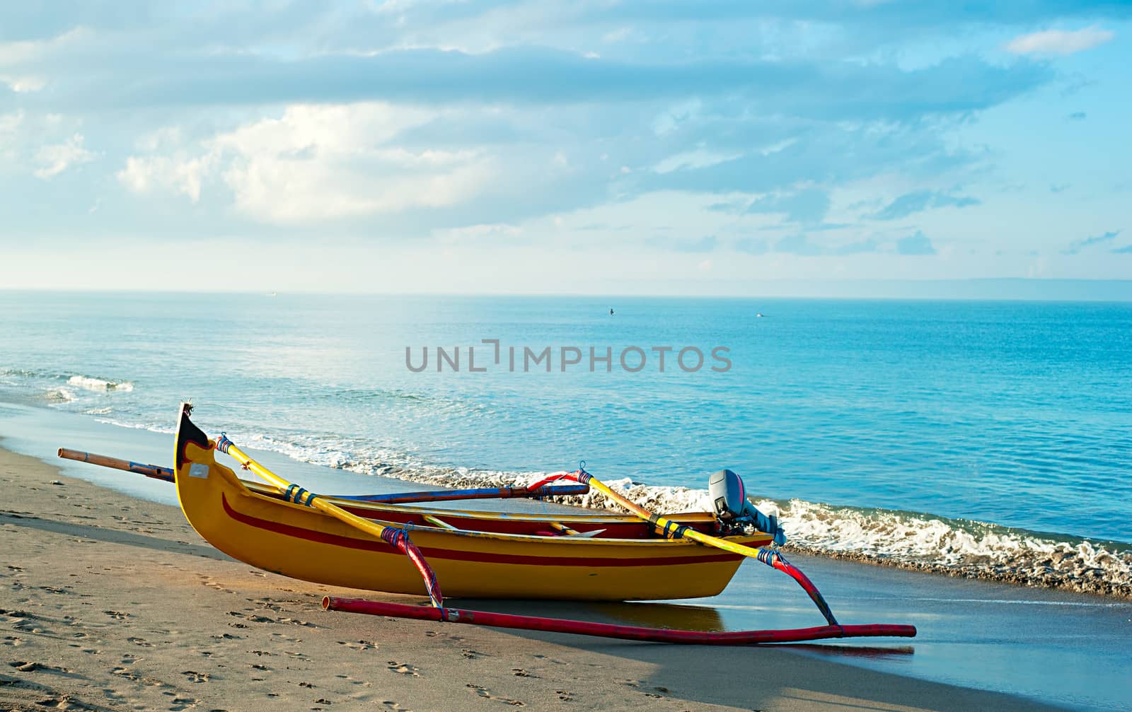 Traditional indonesian fishing boat on Bali ocean beach at sunrise