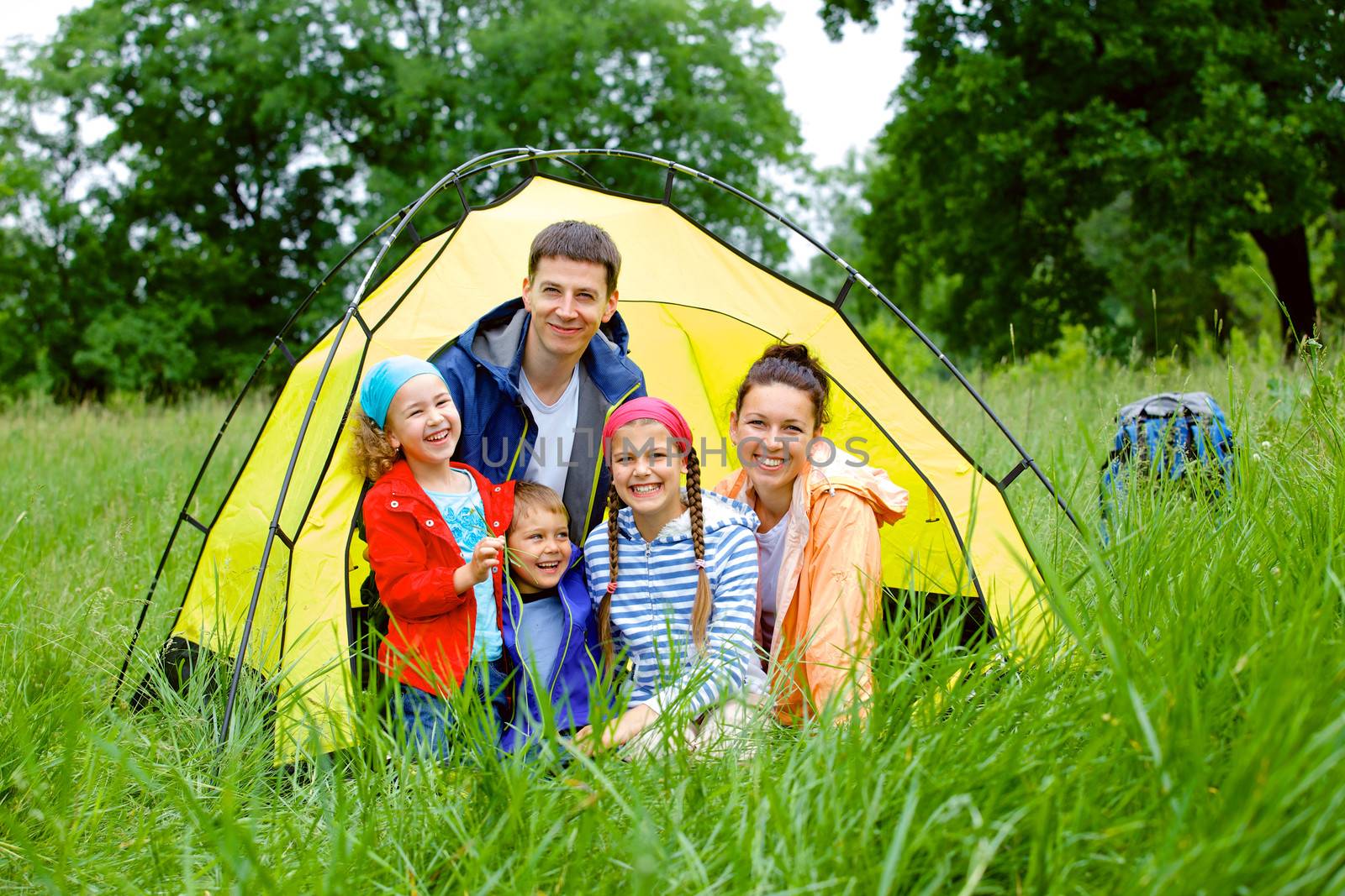 Family with three kids in tent in camping on the nature.