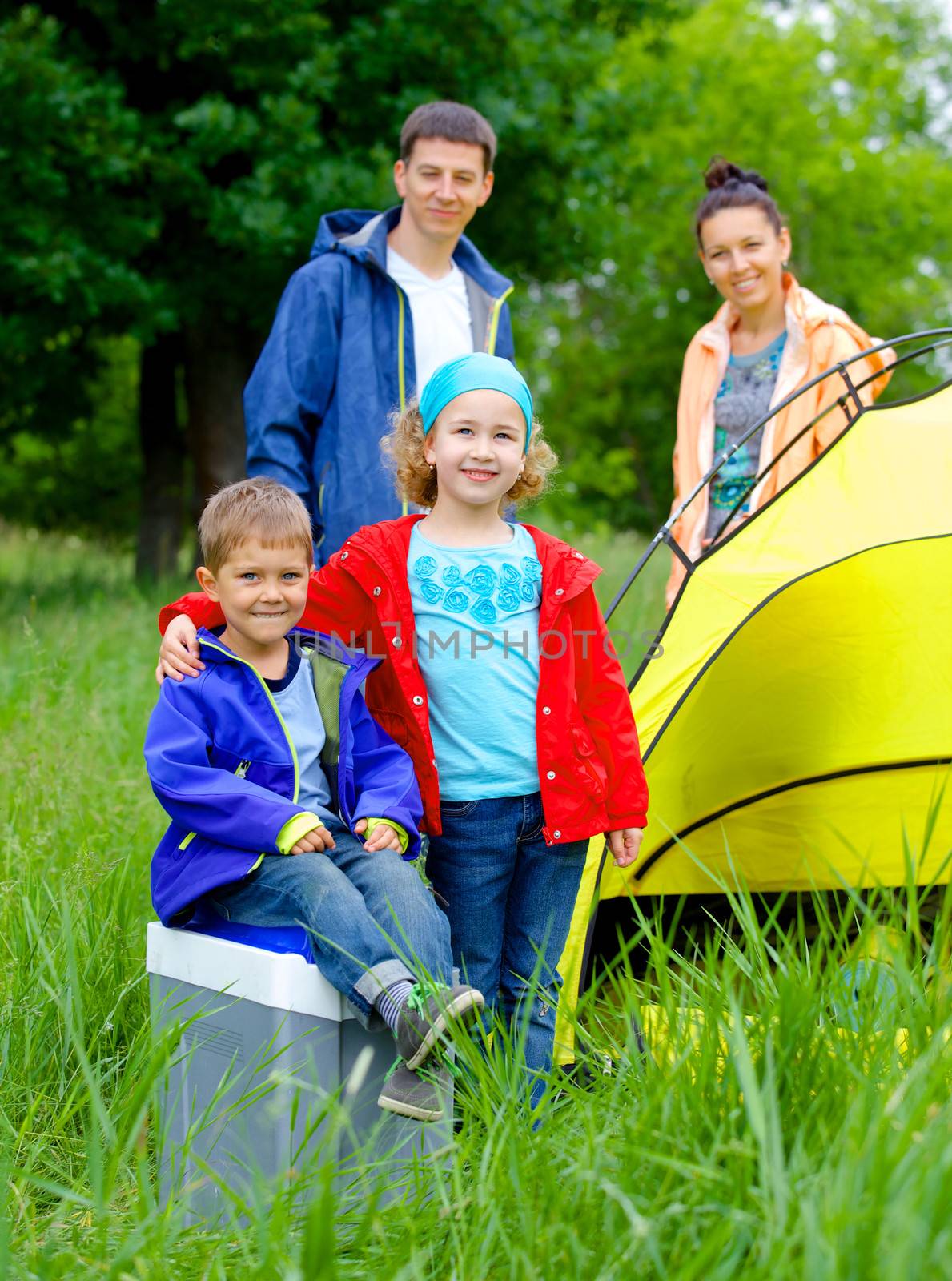 Summer, family camping - lovely sister and brother with parents near camp tent. Vertical view